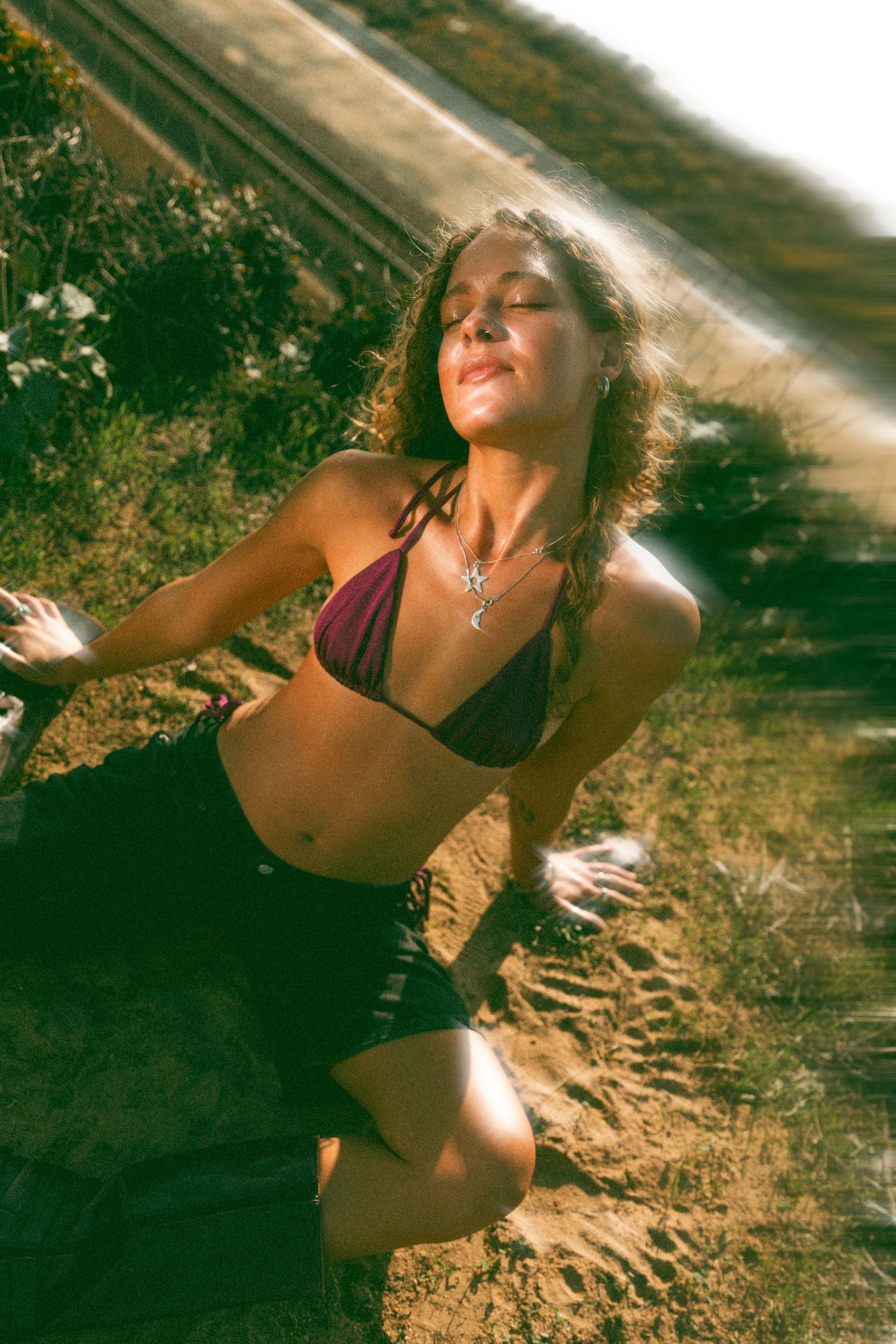 Sun-drenched outdoor portrait featuring a bikini and natural lighting on a coastal trail.