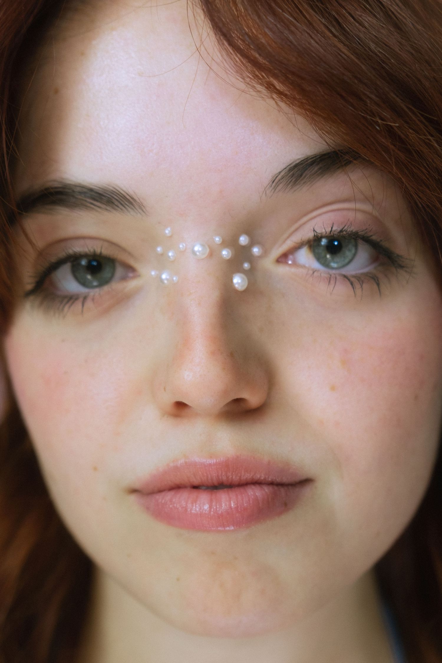 Ethereal beauty portrait with sparkly face decorations and natural makeup.