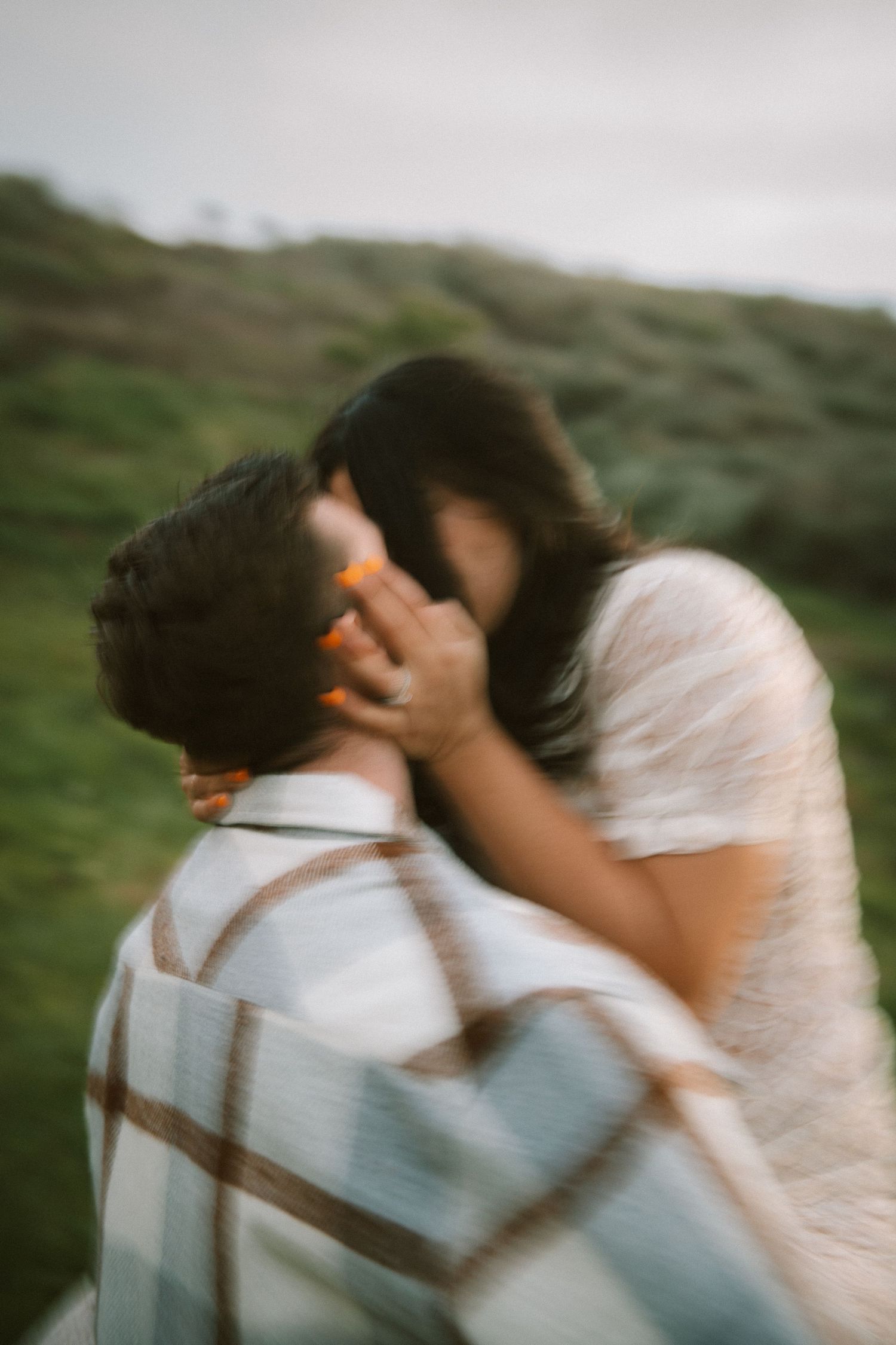 An intimate embrace captured in motion blur against rolling hills.