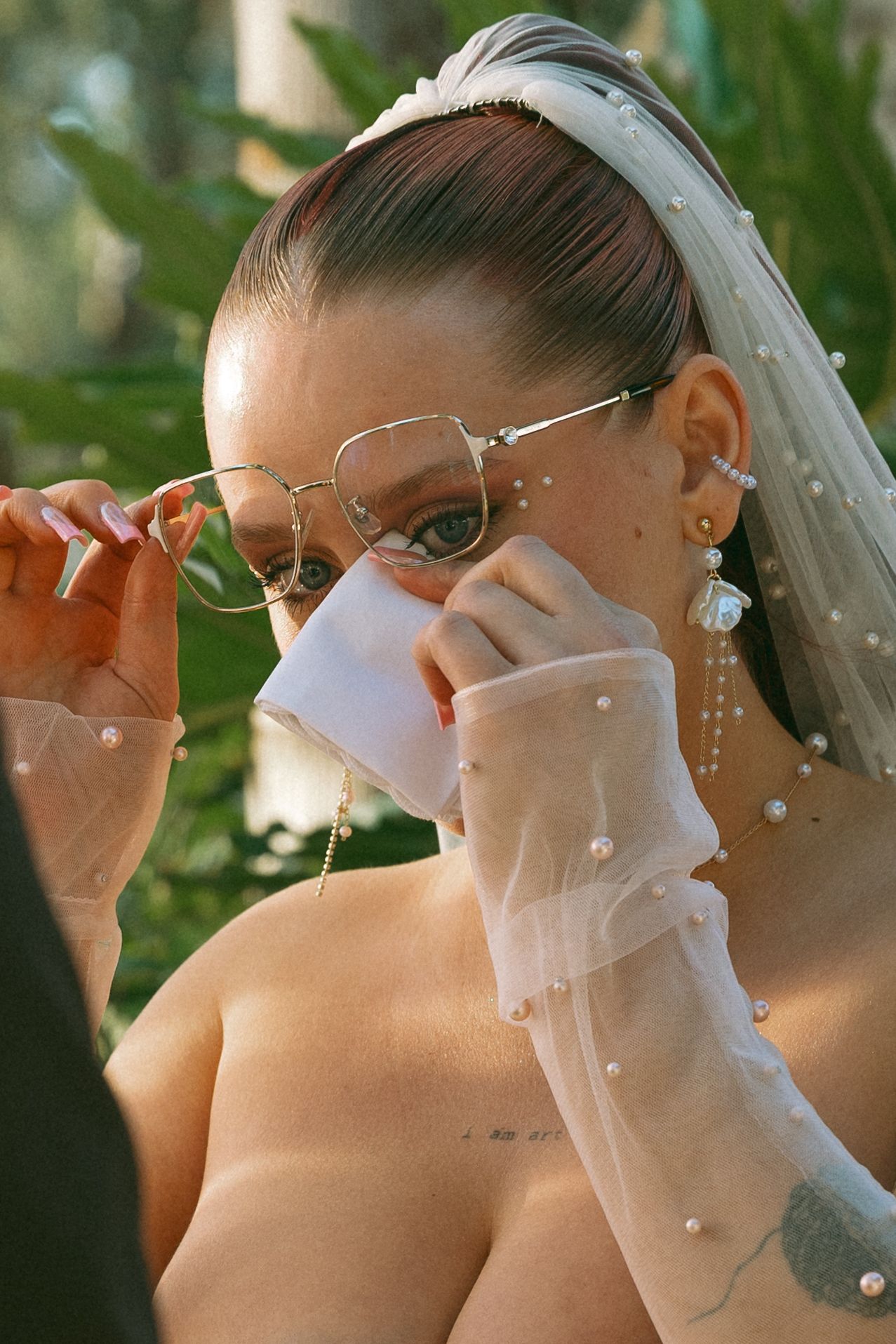 Bride wiping tears with tissue during emotional wedding ceremony moment.