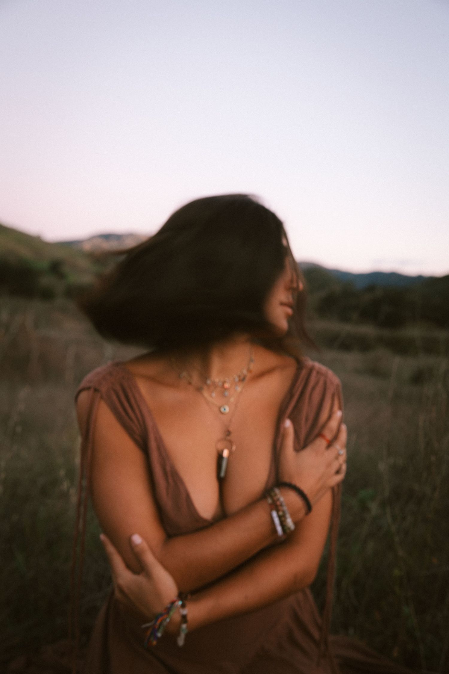 Artistic portrait in brown dress with jewelry at dusk.