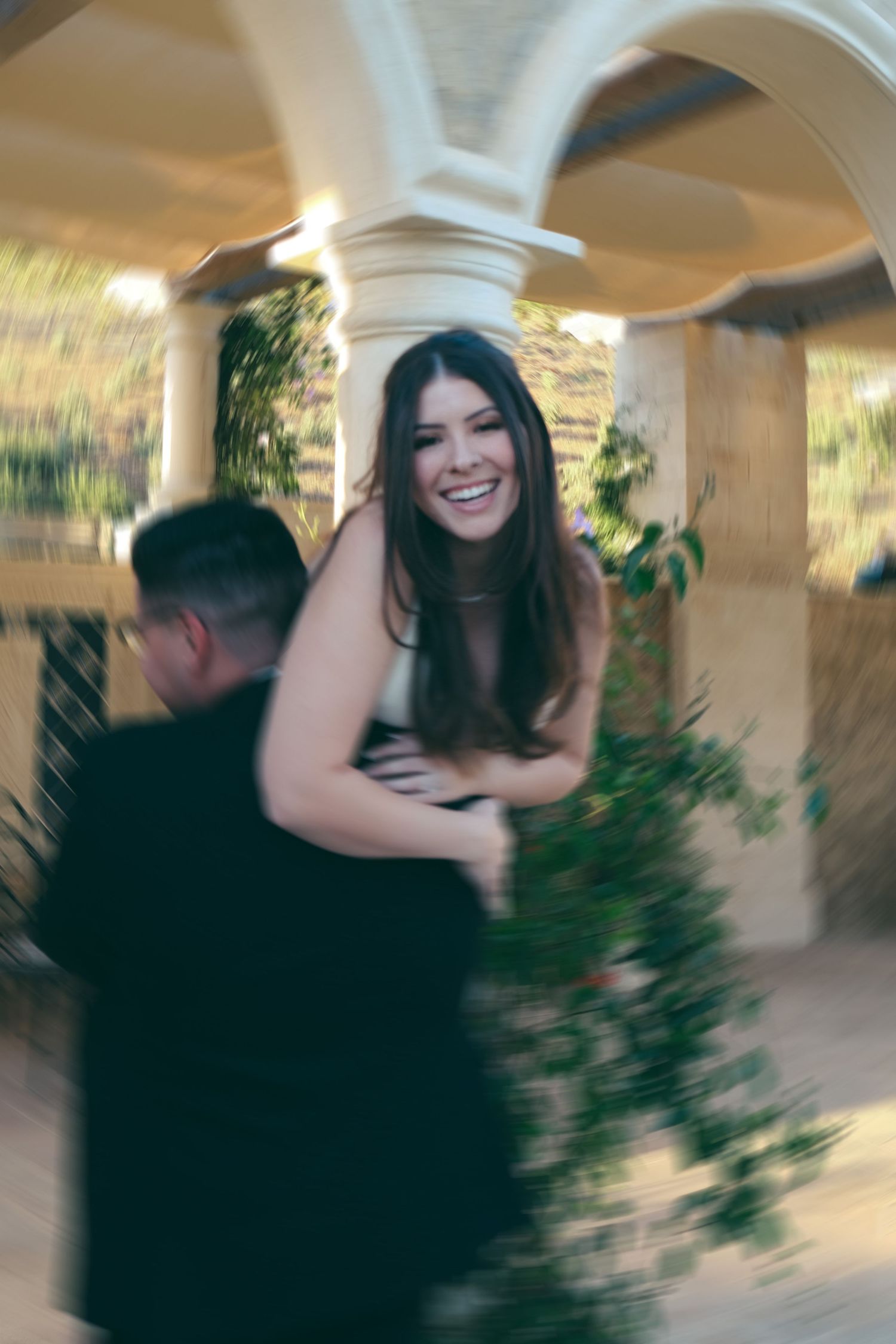 Blurred motion capture of dancing couple under stone archway.