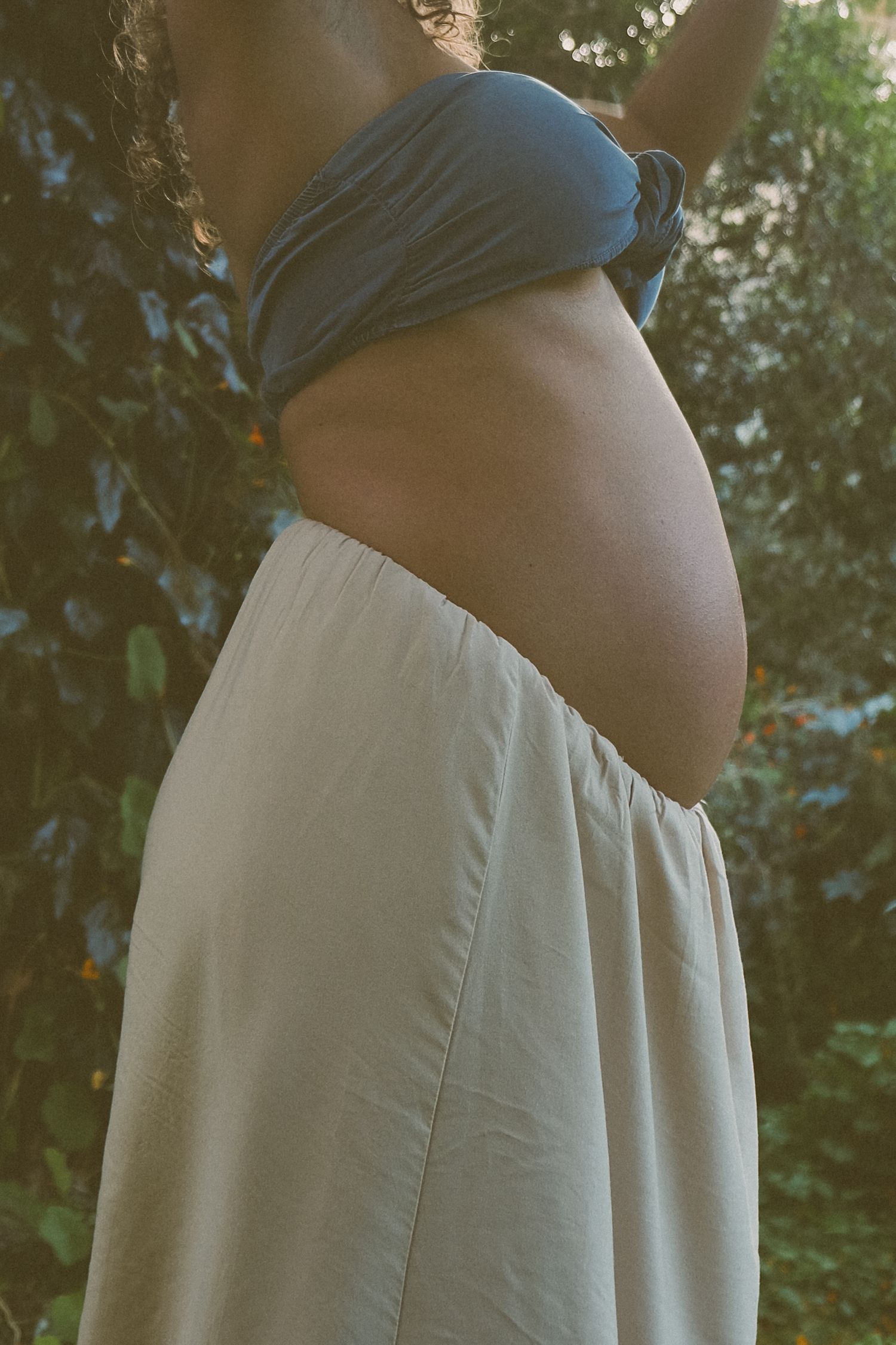 A side view silhouette shows a flowing cream-colored dress against a leafy backdrop.