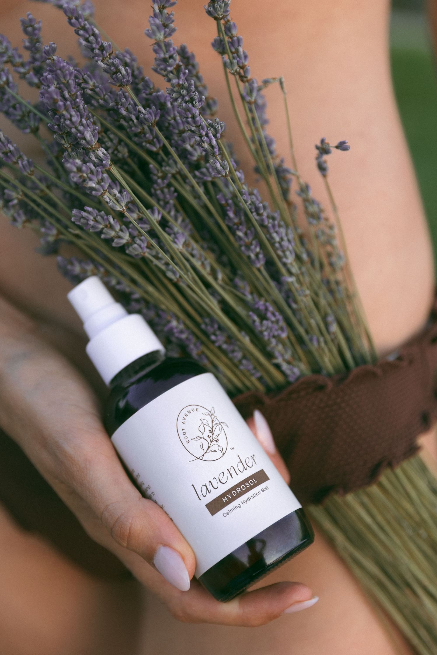 Close-up of hands holding lavender spray bottle with fresh lavender bouquet.