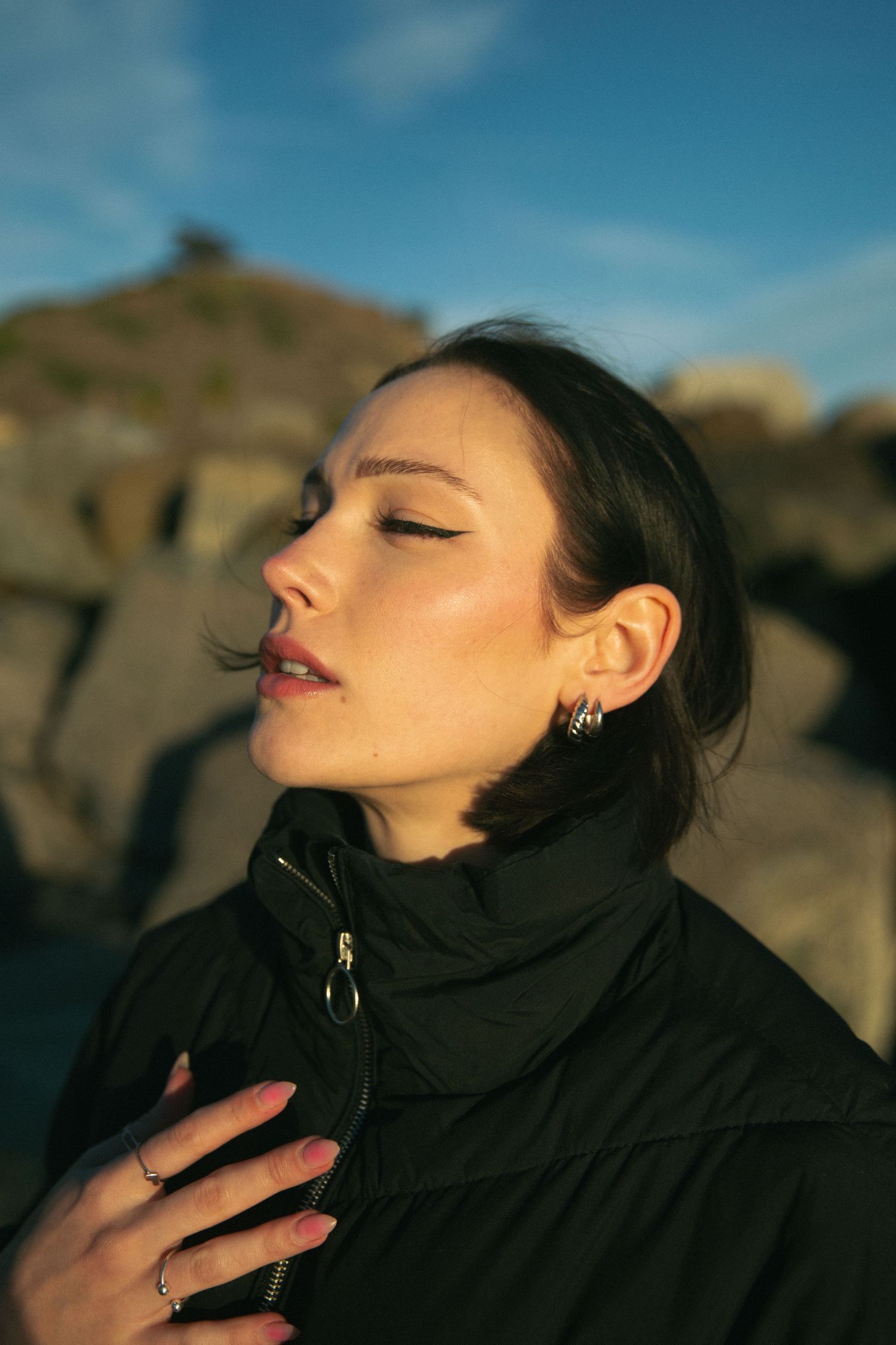 Dramatic outdoor portrait against rocky landscape in golden sunlight.