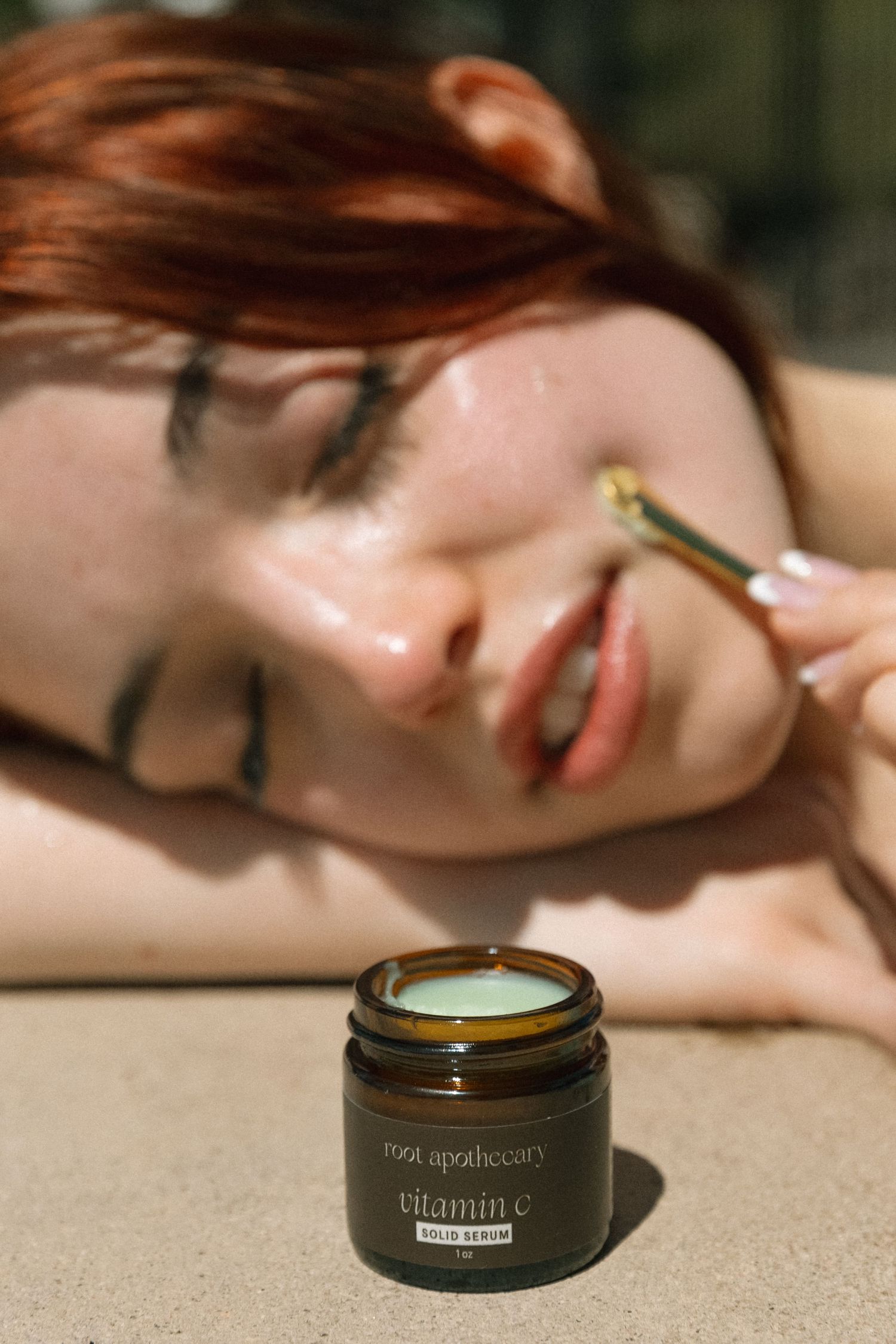 Close-up of dark glass beauty product containers with vitamin e labeling on neutral background.