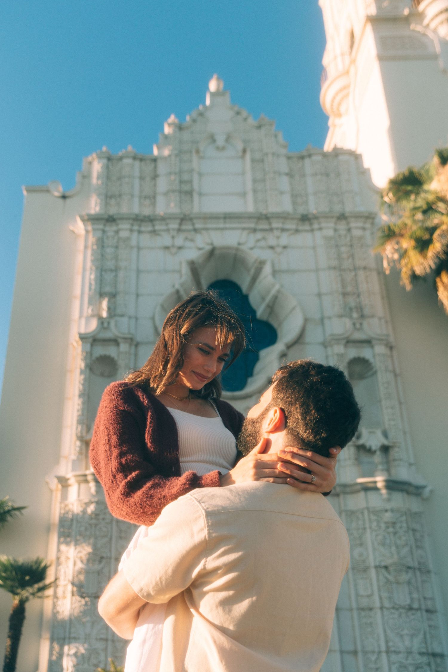A tender moment captured between a couple against the backdrop of a historic white church building.