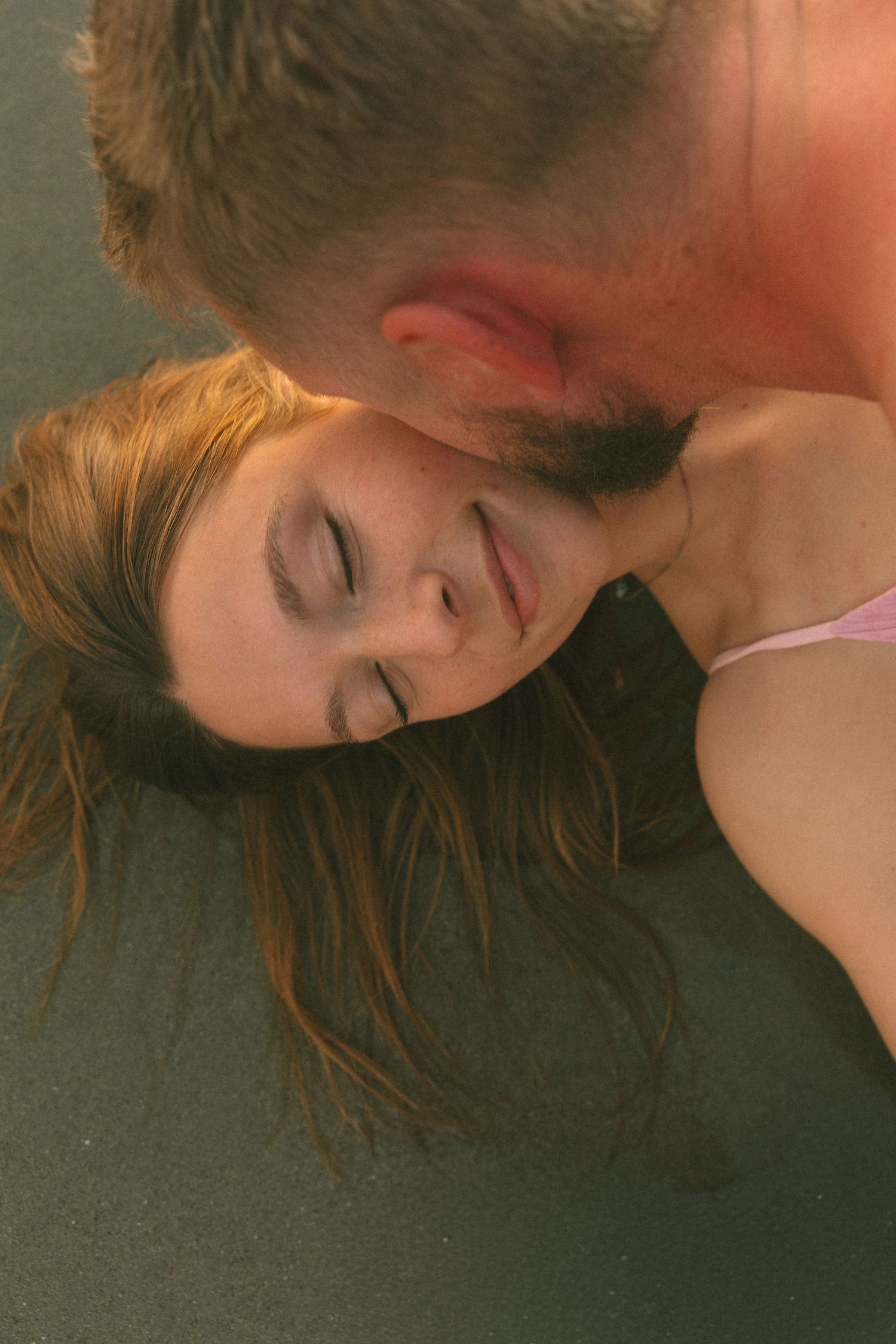 Intimate close-up portrait of a couple sharing a tender moment against a dark background.