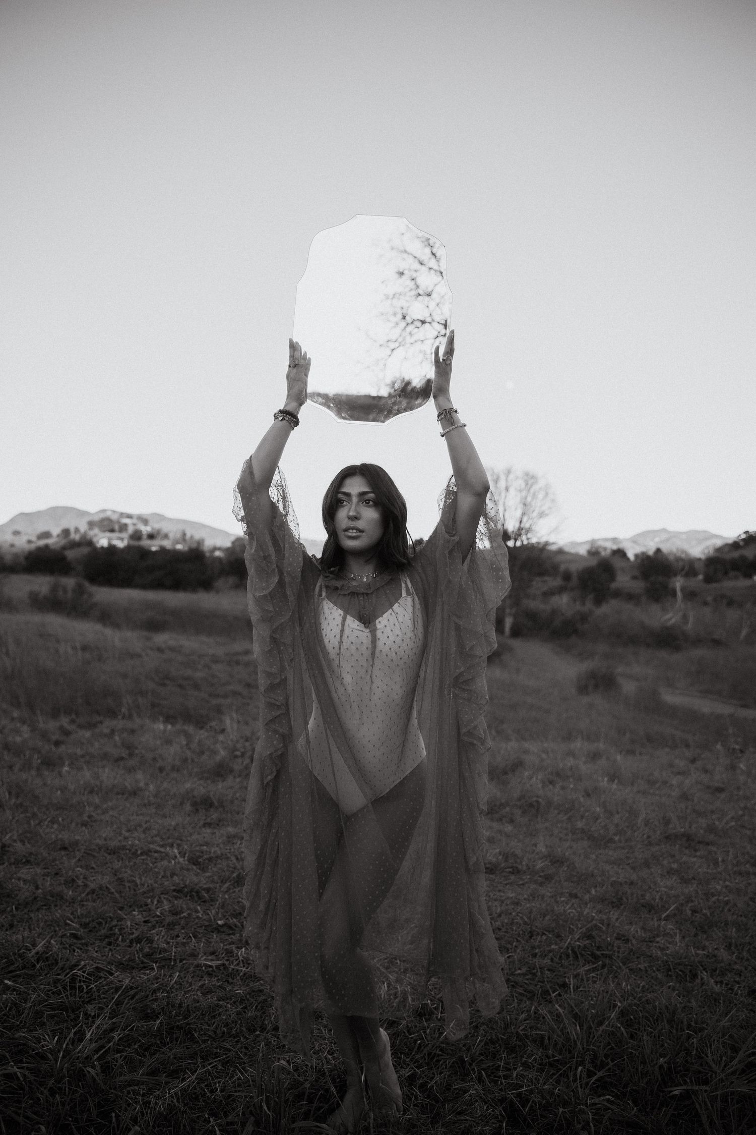 Black and white series showing a figure in flowing garments with raised arms against a rural backdrop.