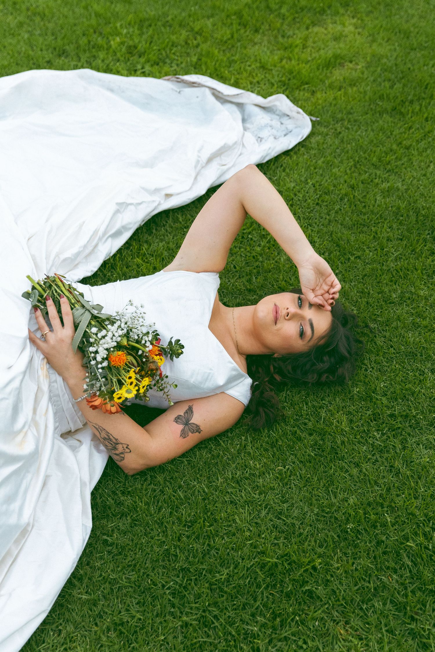 A white dress spread out on vibrant green grass with floral accents.