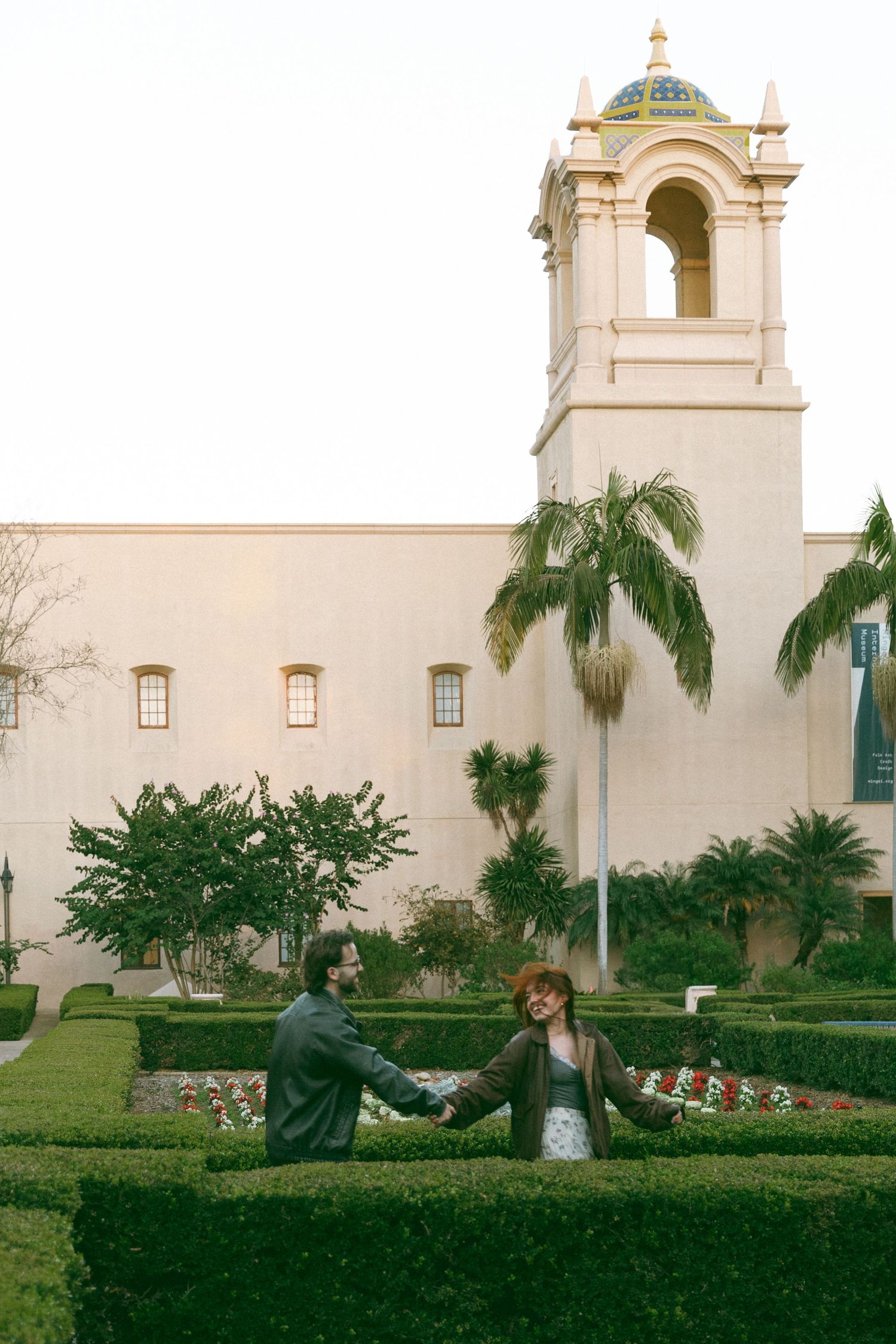 Dancing silhouettes against white mission-style building and palm trees.