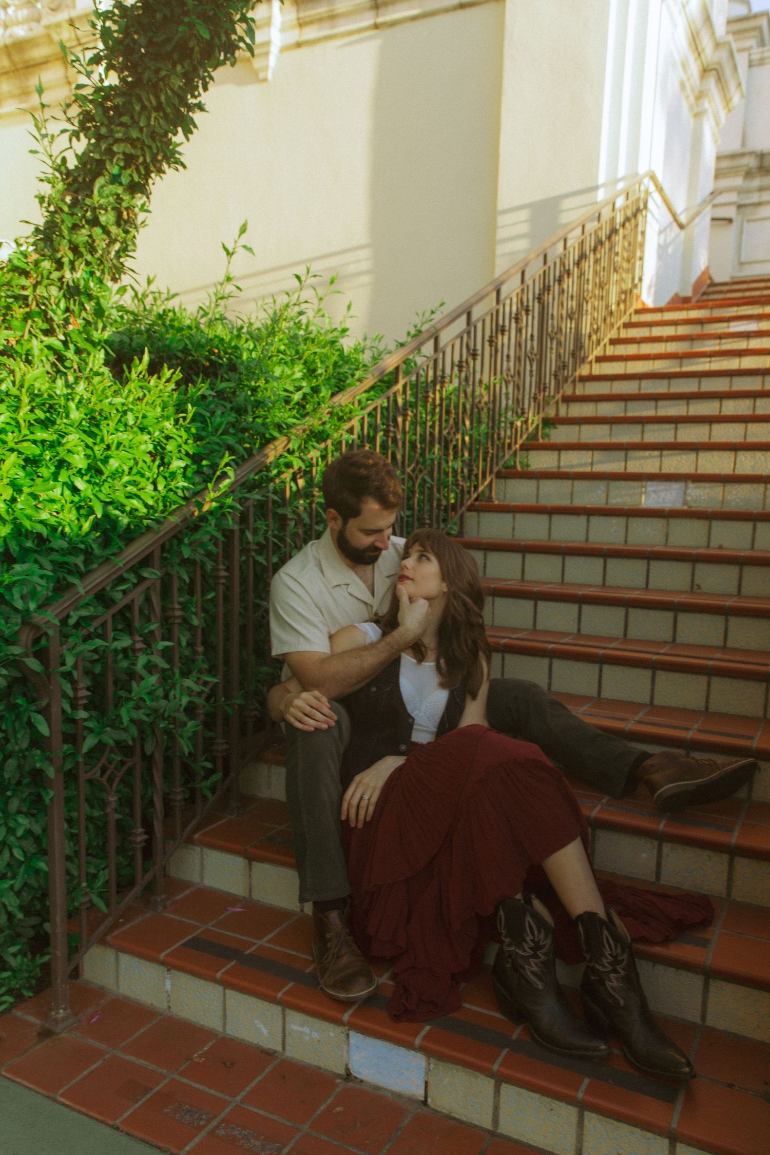 A romantic scene on terracotta steps with decorative iron railings and green foliage.