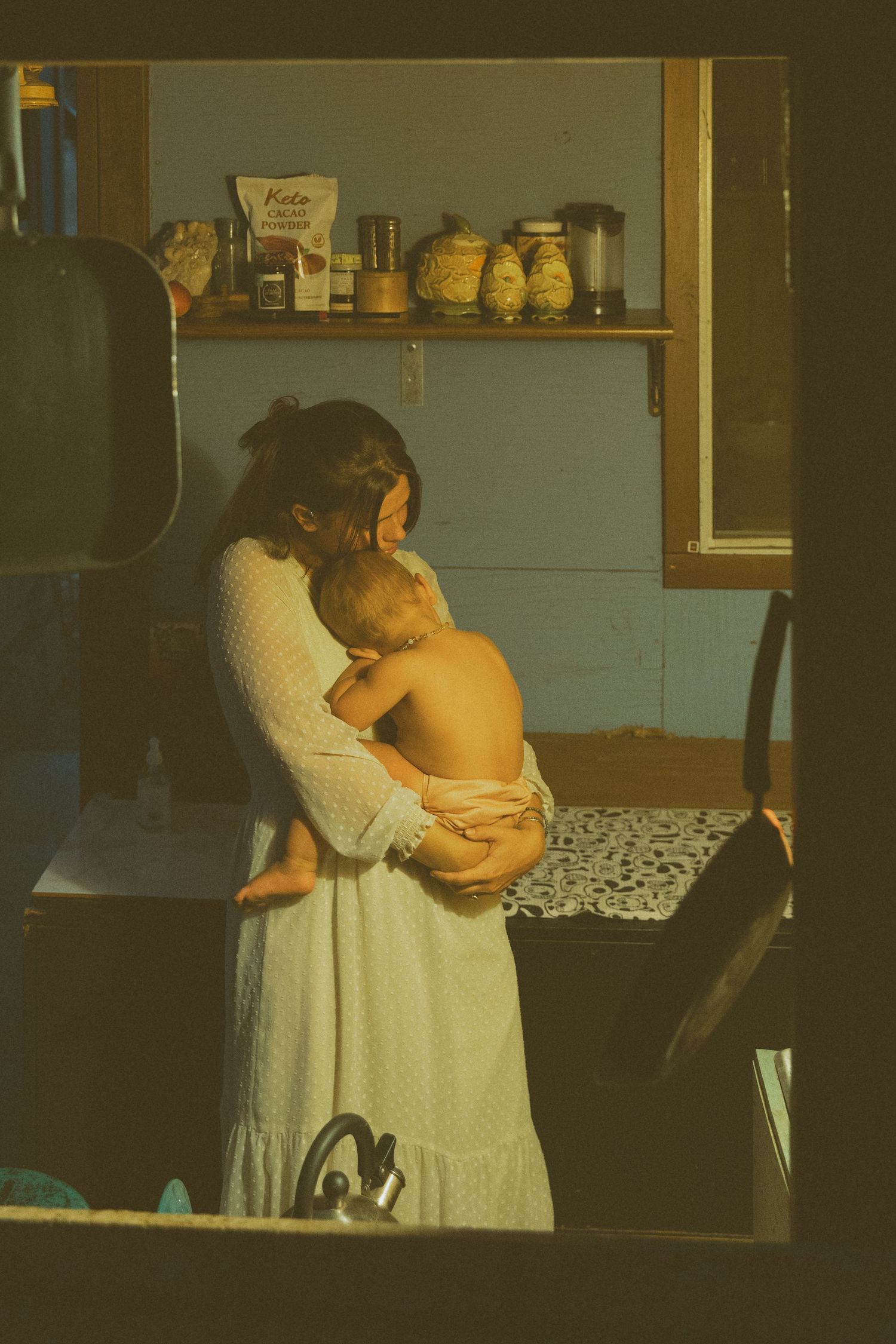 Gentle embrace between caregiver and baby in a softly lit home environment.
