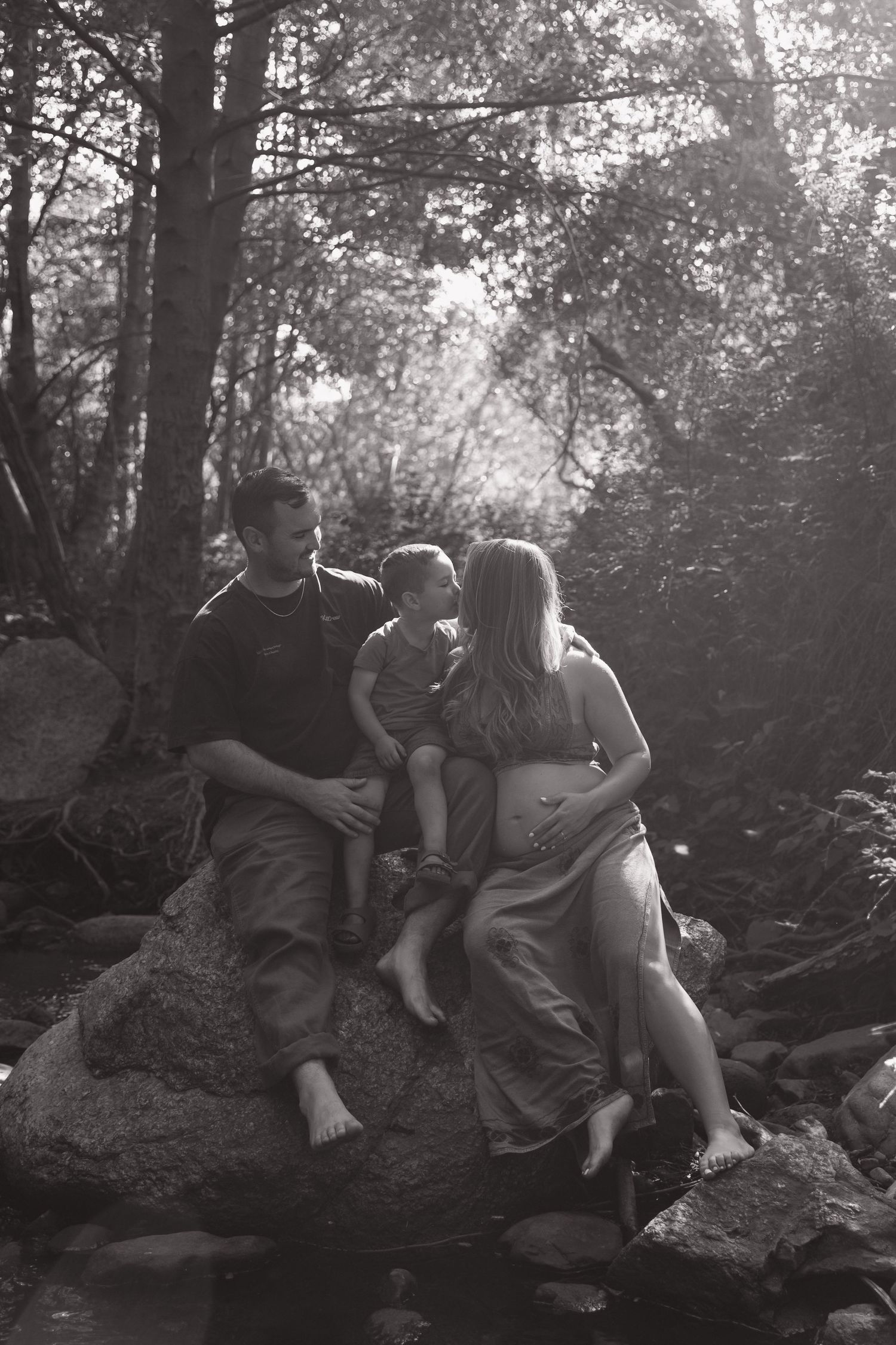 A black and white family portrait taken in a forest setting.