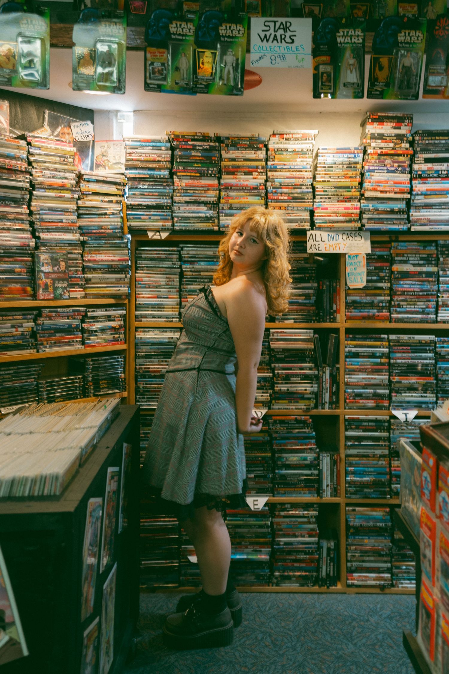A retro-styled photo showing someone browsing Star Wars merchandise and media at a record store.