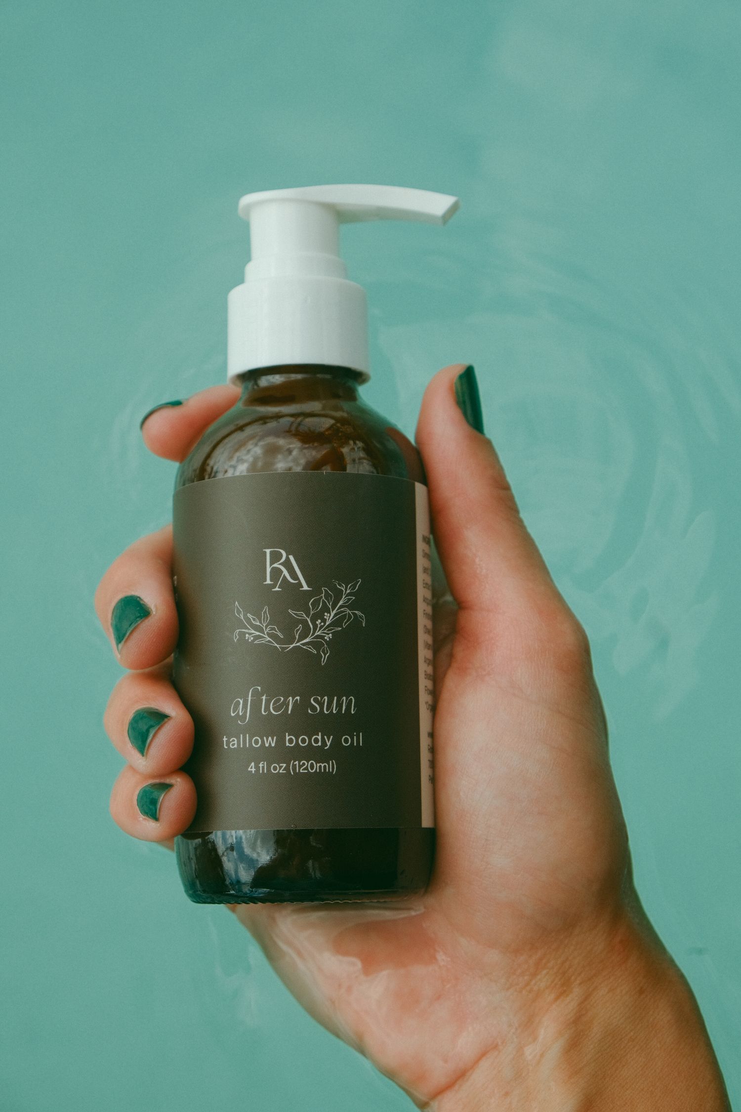 Matte black skincare product bottle with 'after sun' text being held against turquoise background.