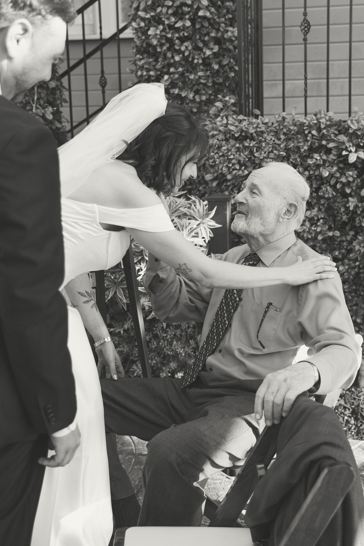 Wedding celebration outdoors with guests interacting near decorative garden fence.