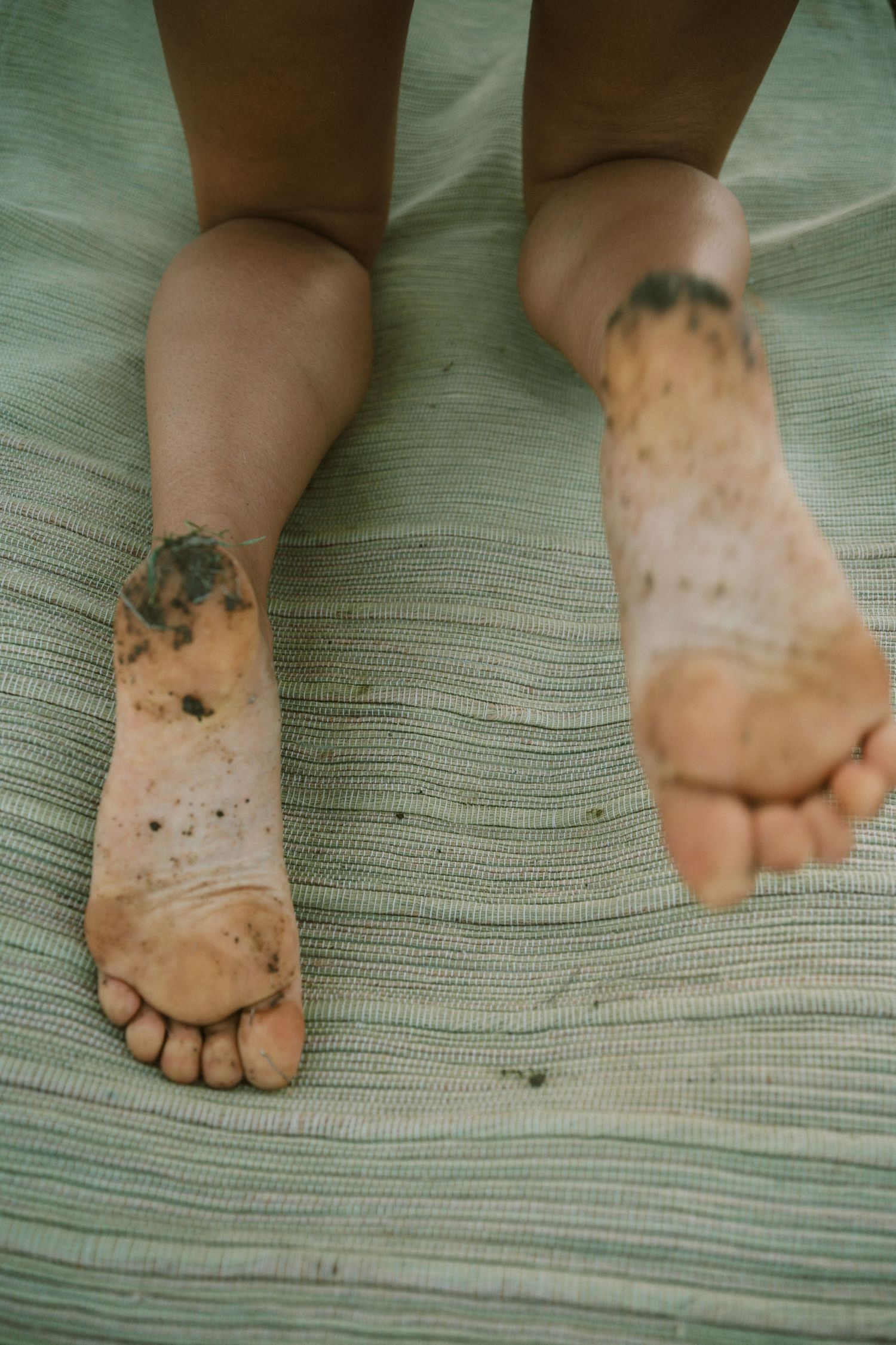 Close-up sequence of muddy feet on a striped green textile surface.