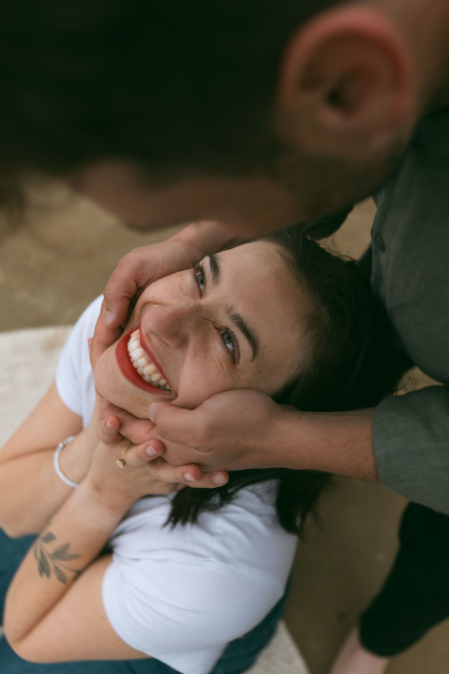 Close-up portrait of a person in white laughing while lying down outdoors.