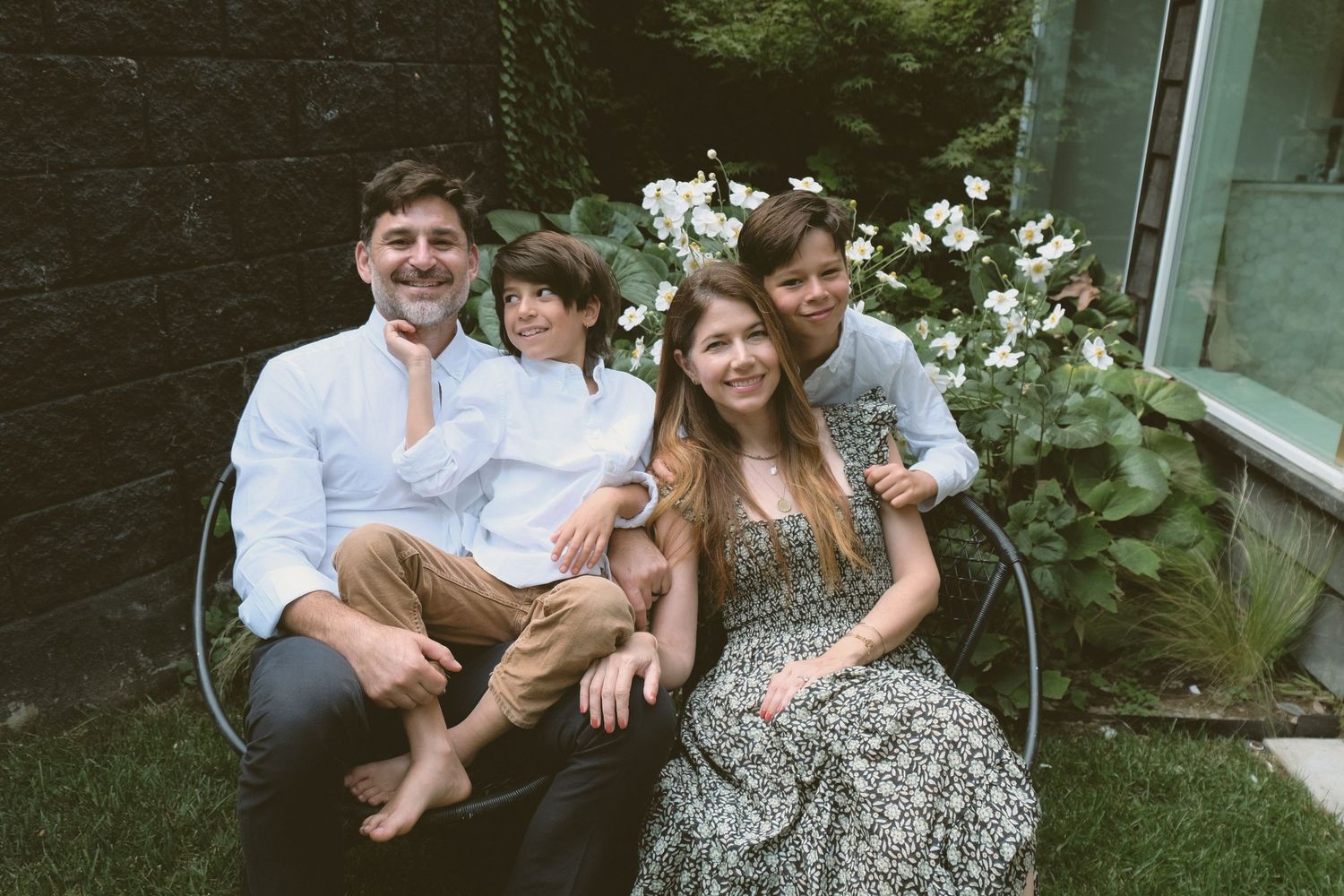 A family enjoys a playful moment together in a backyard garden setting.