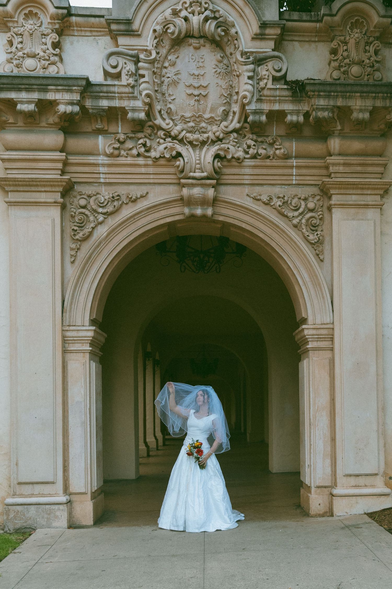 A white dress photographed in front of ornate classical architecture with arched doorways.