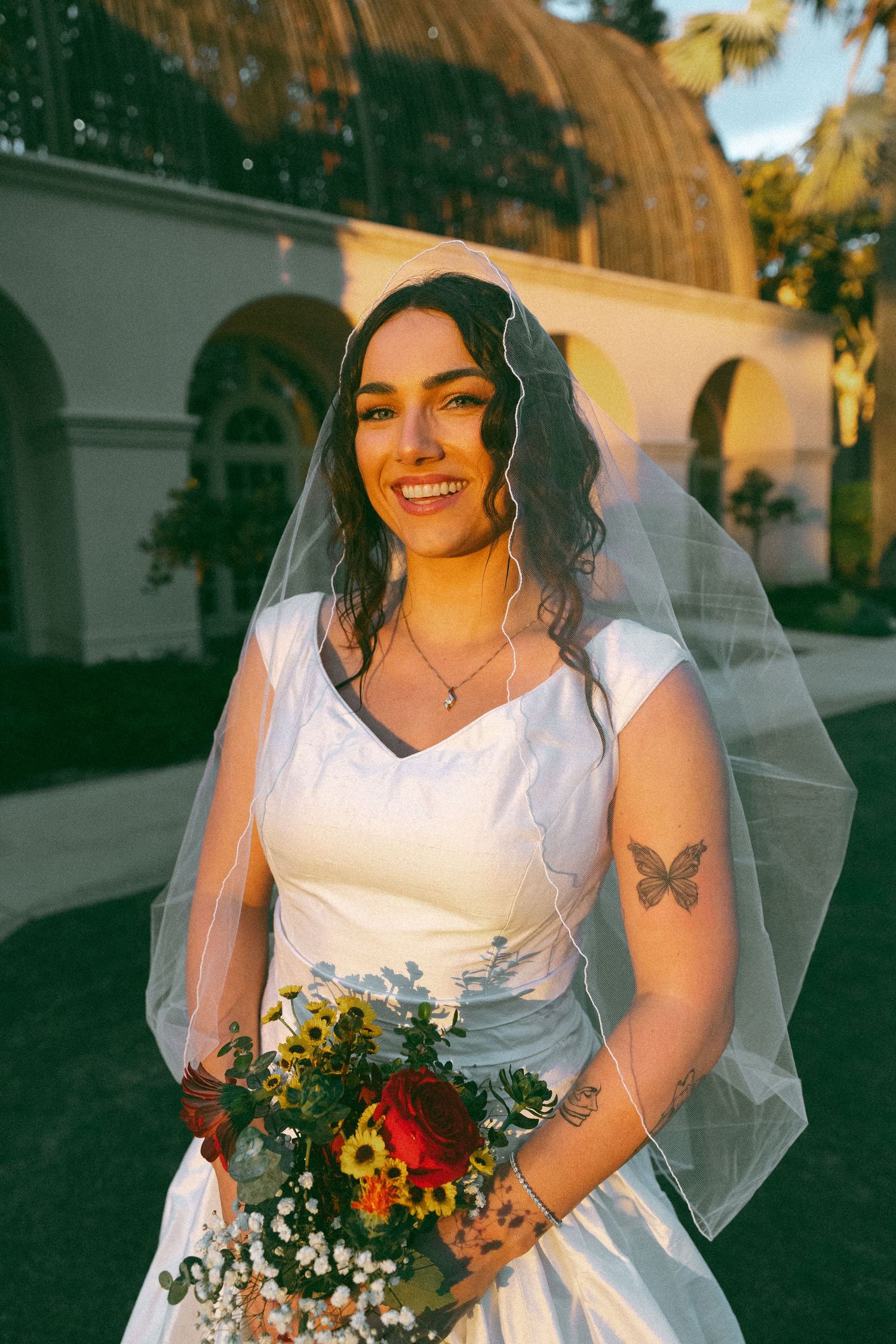 A bridal photoshoot featuring a white dress and colorful bouquet in golden hour lighting.