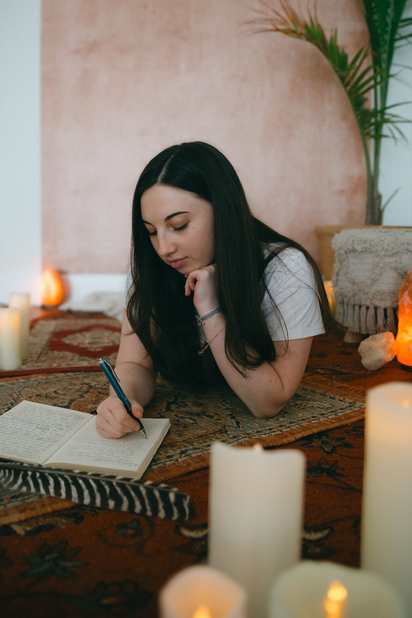 Candlelit journaling session on patterned rug with white candles creating ambient atmosphere.