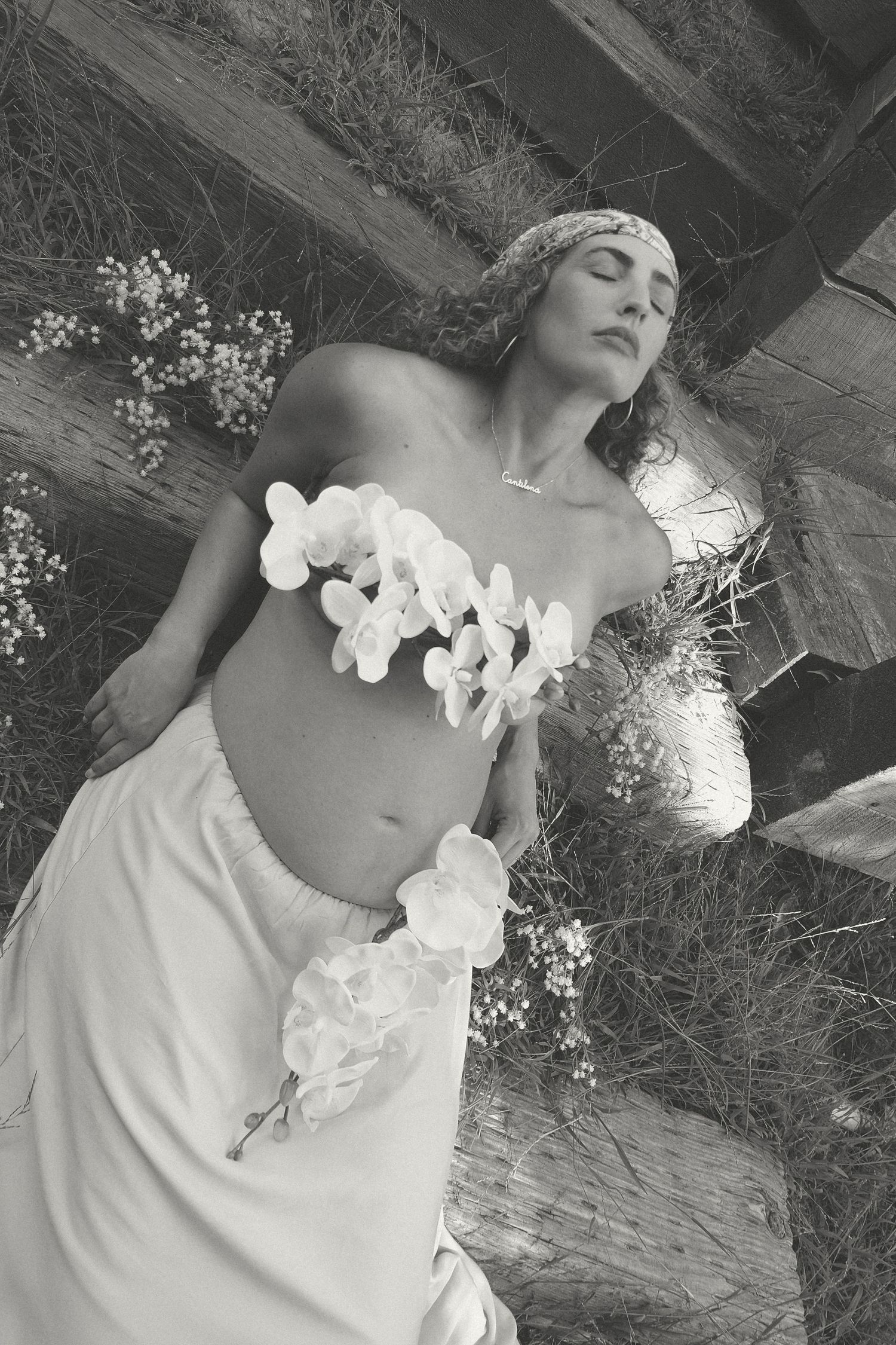 Dramatic black and white portrait with white orchids and rustic wooden background.