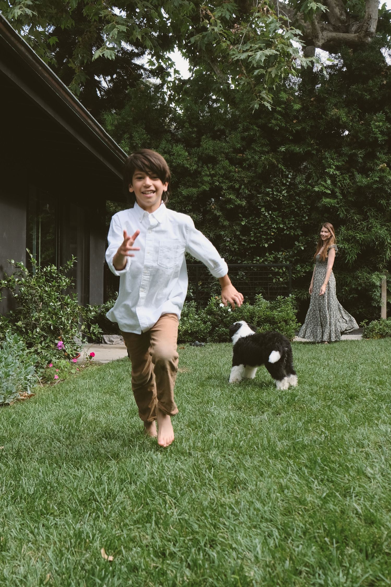 A child jumps and plays energetically on a grassy lawn.