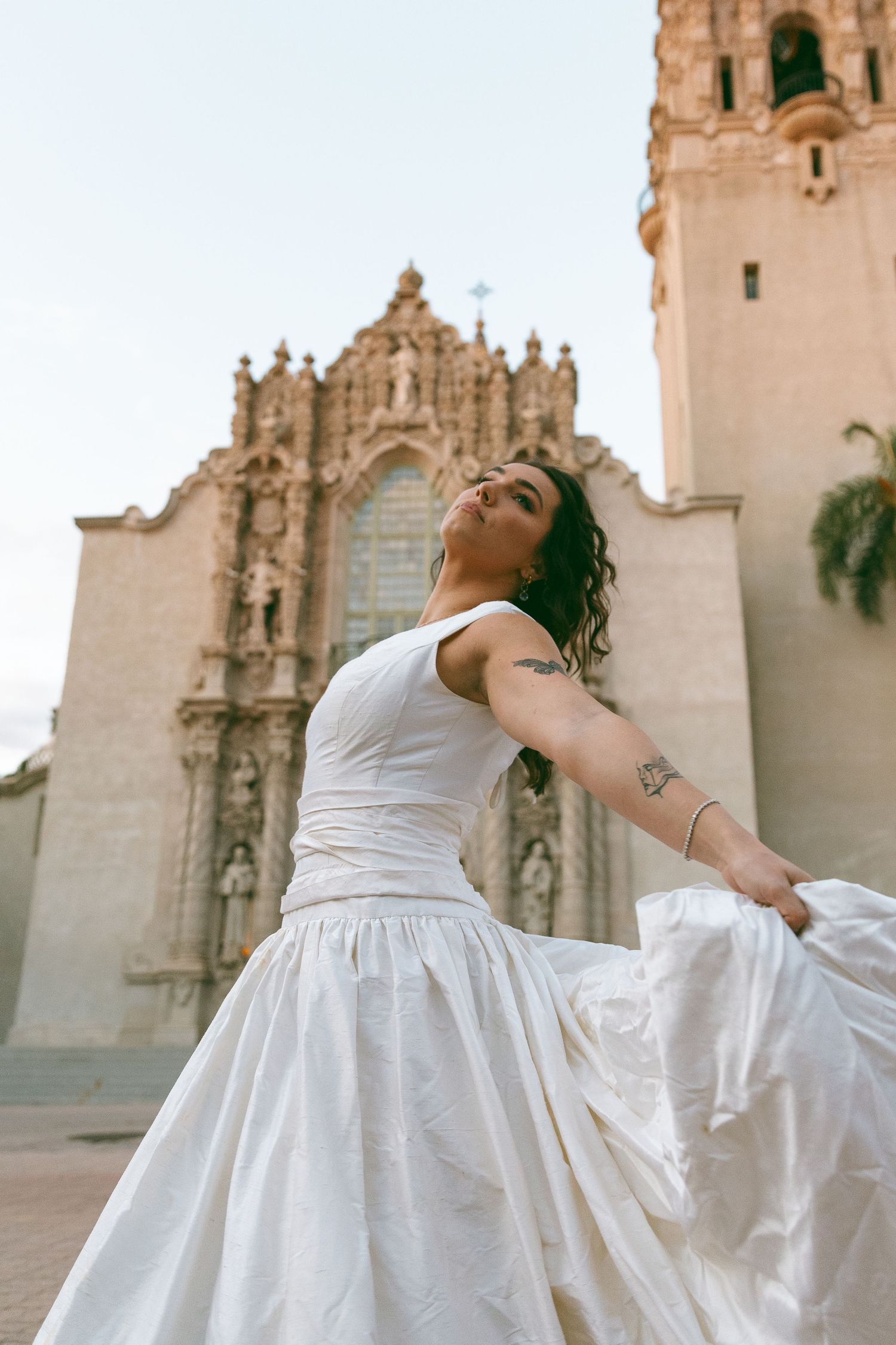 White wedding dress flowing gracefully against historic Spanish colonial architecture background.