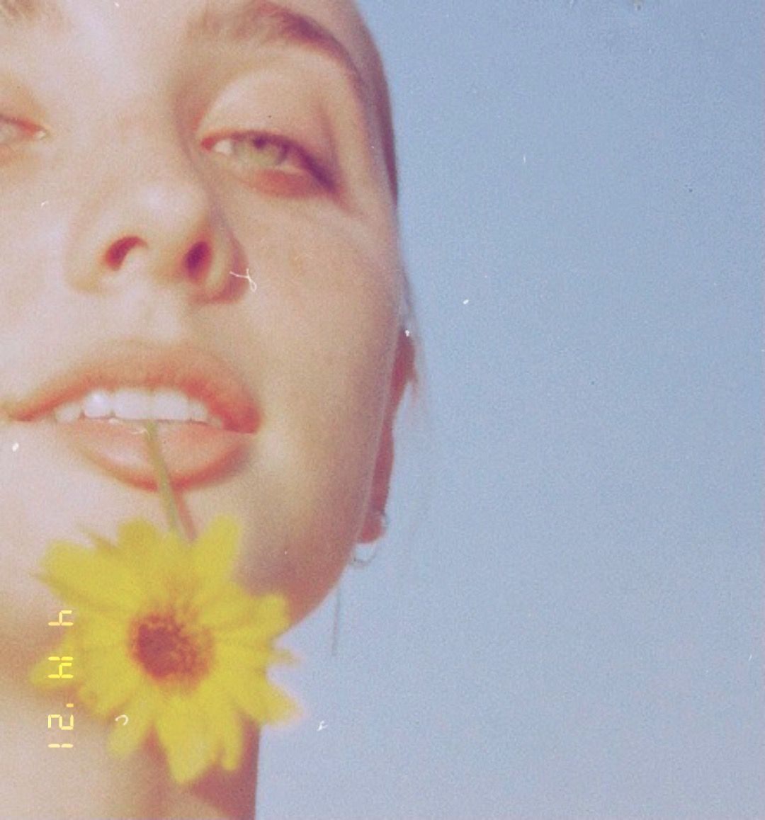 Dreamy summer portrait with yellow sunflower against blue sky.