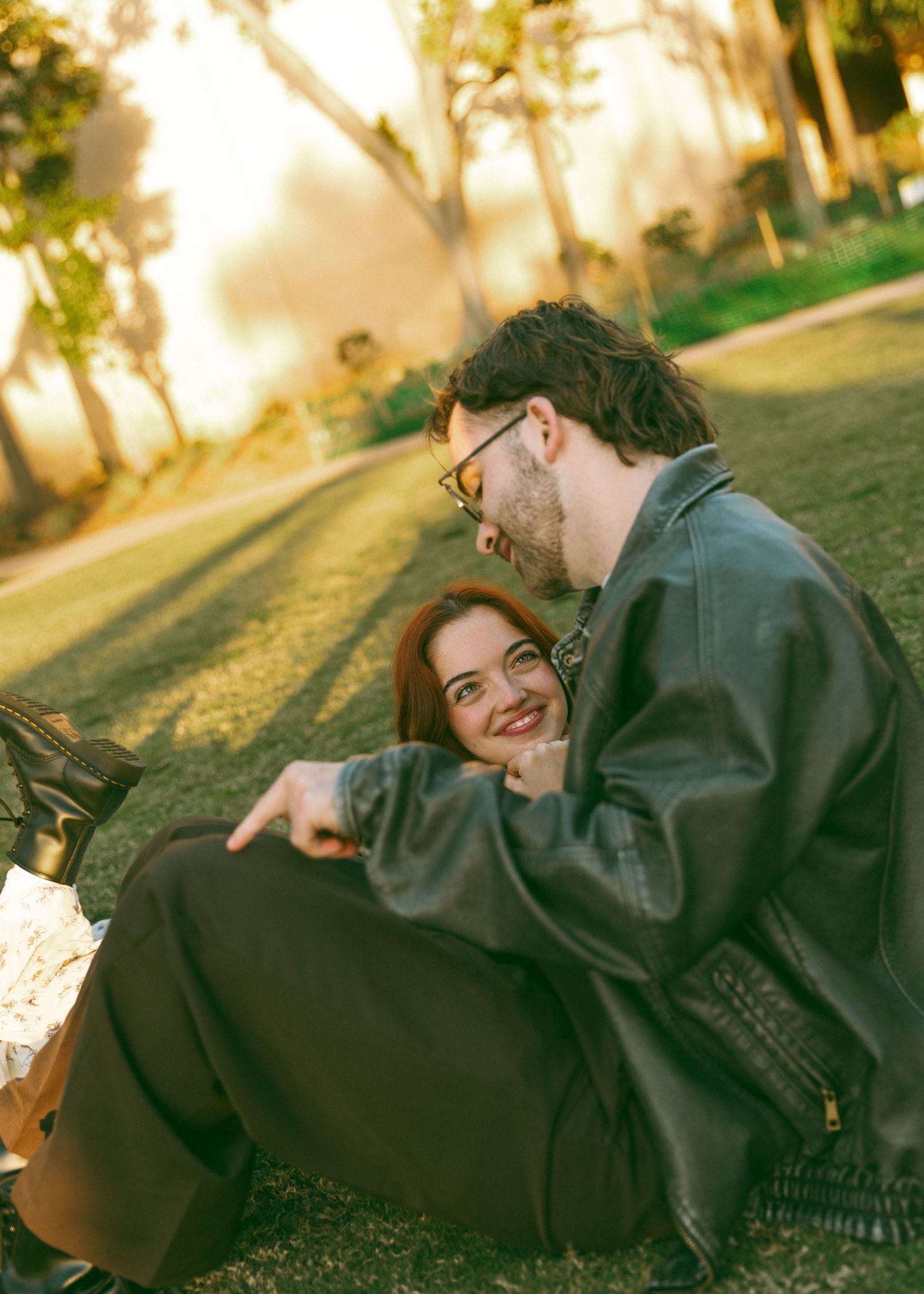 Couple lounging together on grass during golden hour sunset.