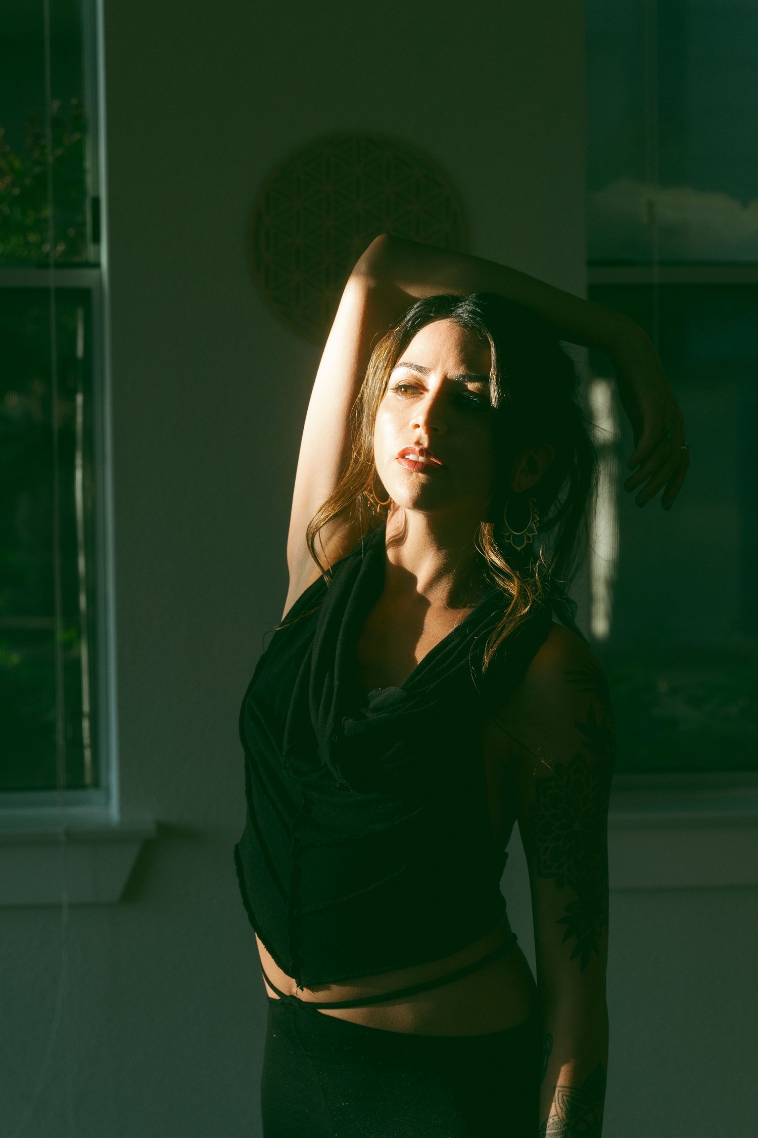 Artistic indoor portrait with dramatic lighting and shadows against a dark green background.