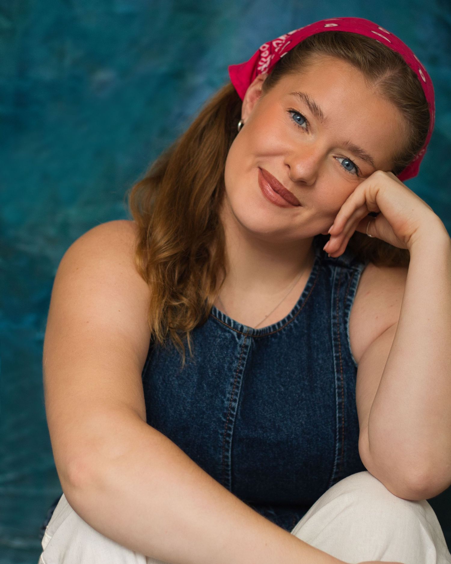 Portrait series in denim dress and red headband against blue backdrop showing various poses and expressions.