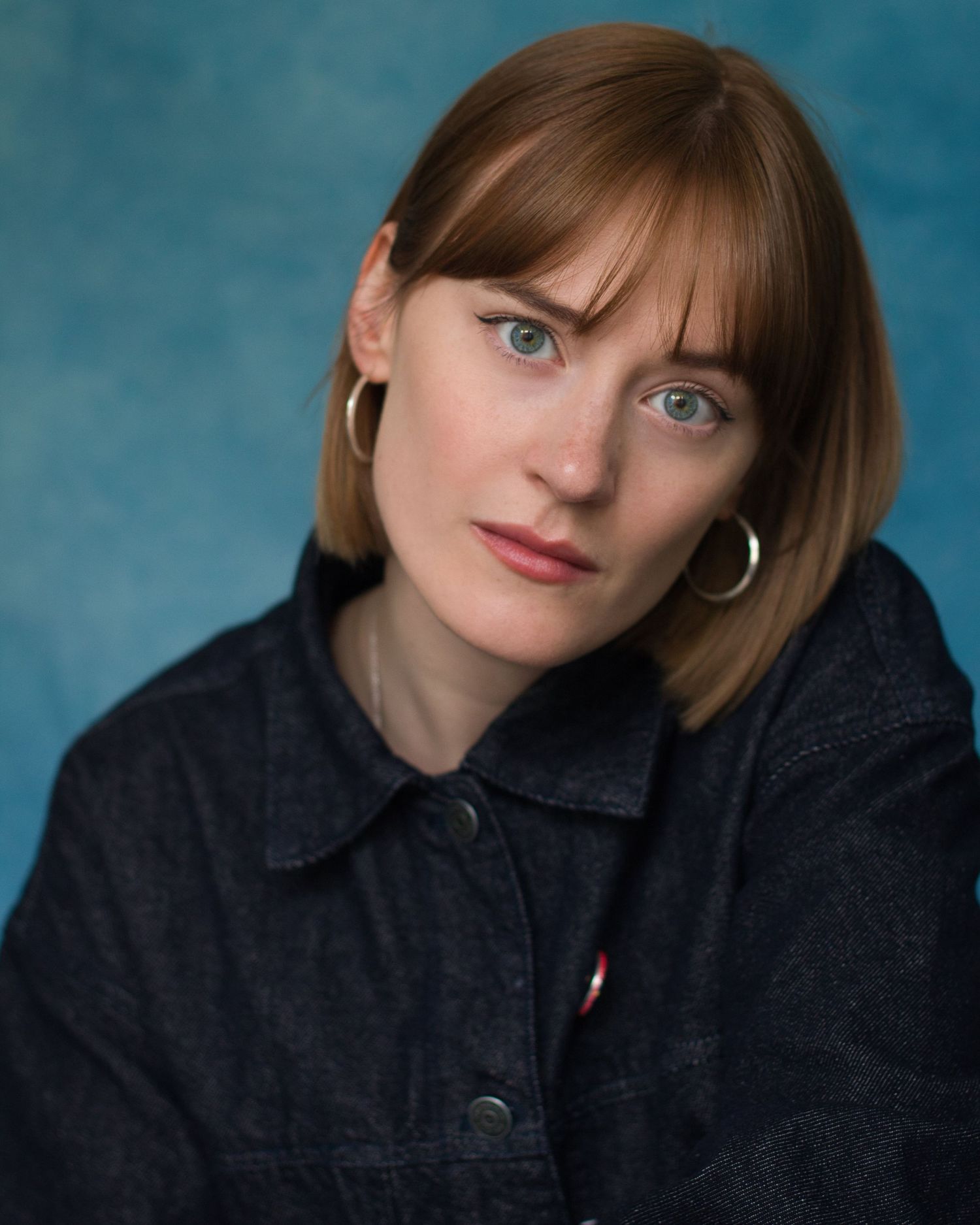 Portrait series in front of teal backdrop showing different poses and expressions while wearing a dark denim jacket.