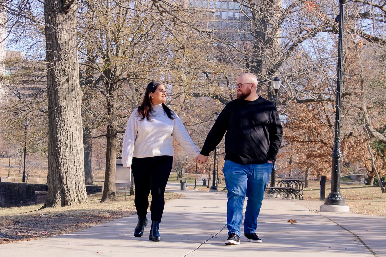A couple walking together on a tree-lined path during autumn.