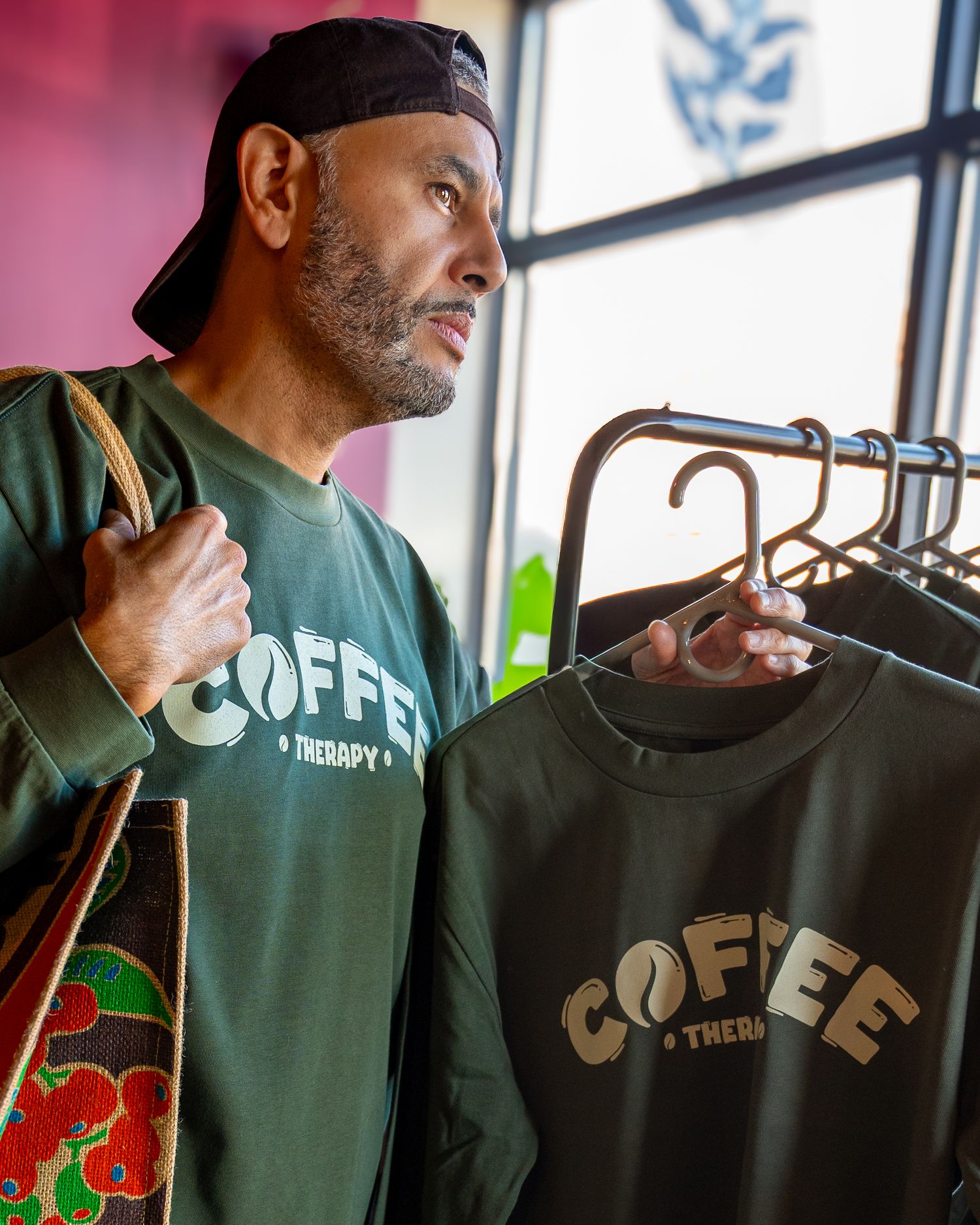 Person in a green coffee-themed t-shirt stands near a window in multiple poses.