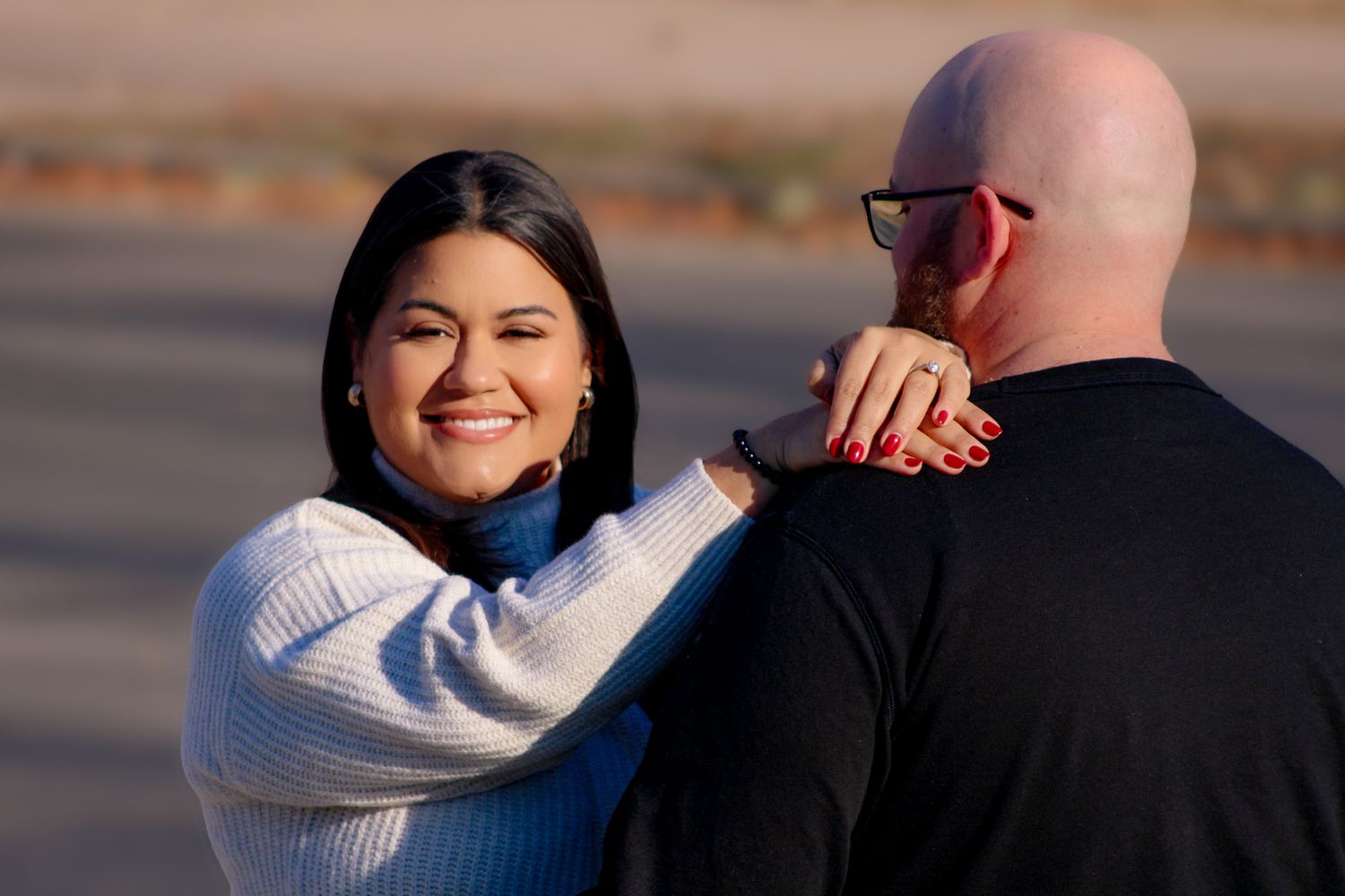 A couple sharing a sweet moment together outdoors while wearing matching white sweaters.
