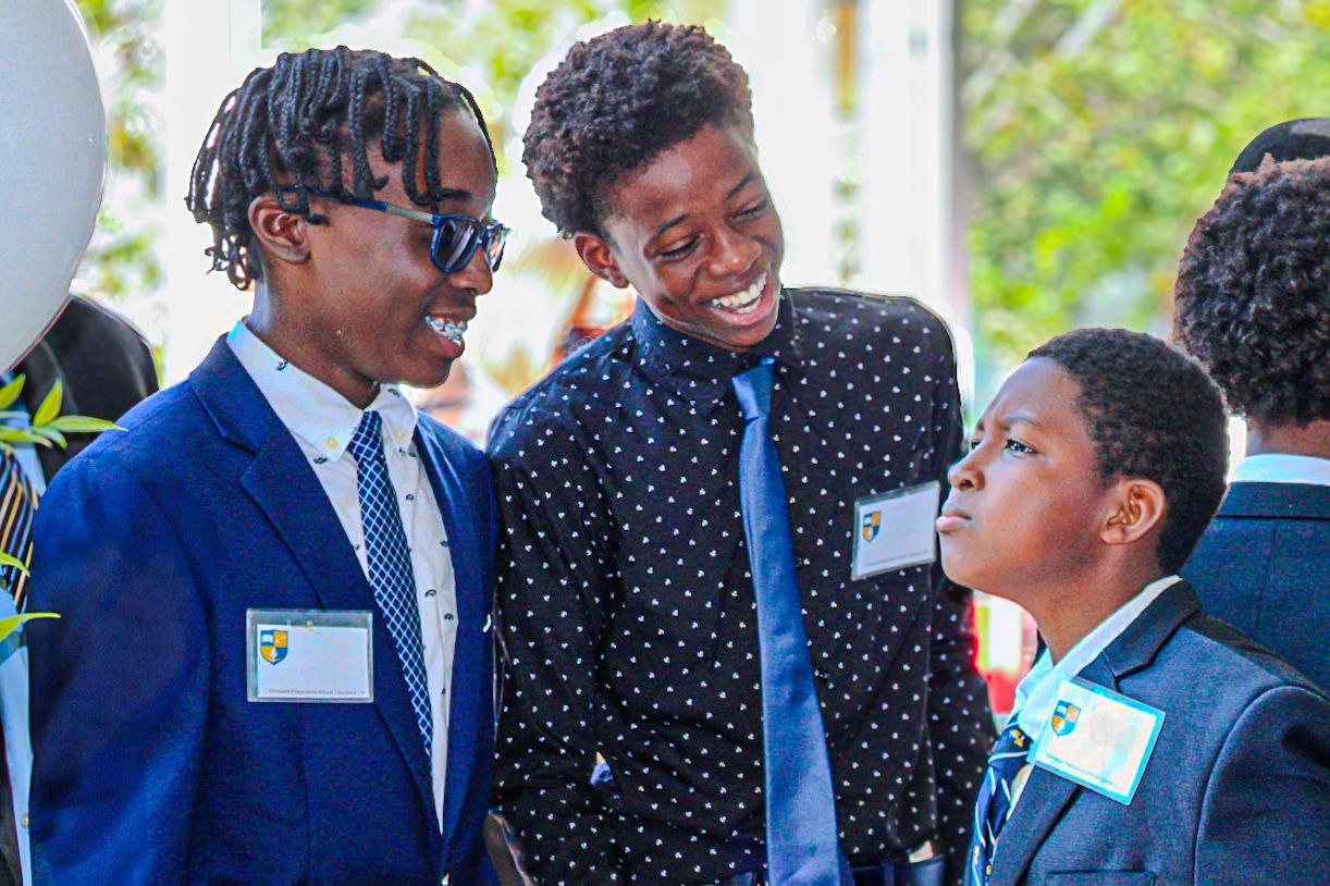 Three young people in formal attire smiling and conversing at an event.
