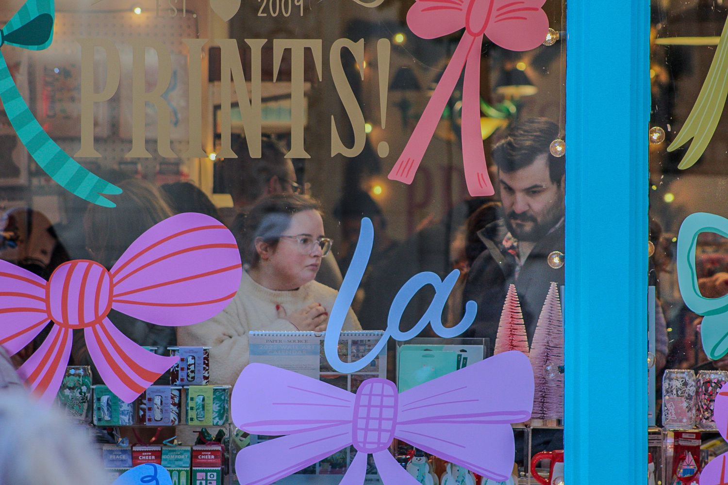 Storefront window decorated with pink and purple bow decorations.