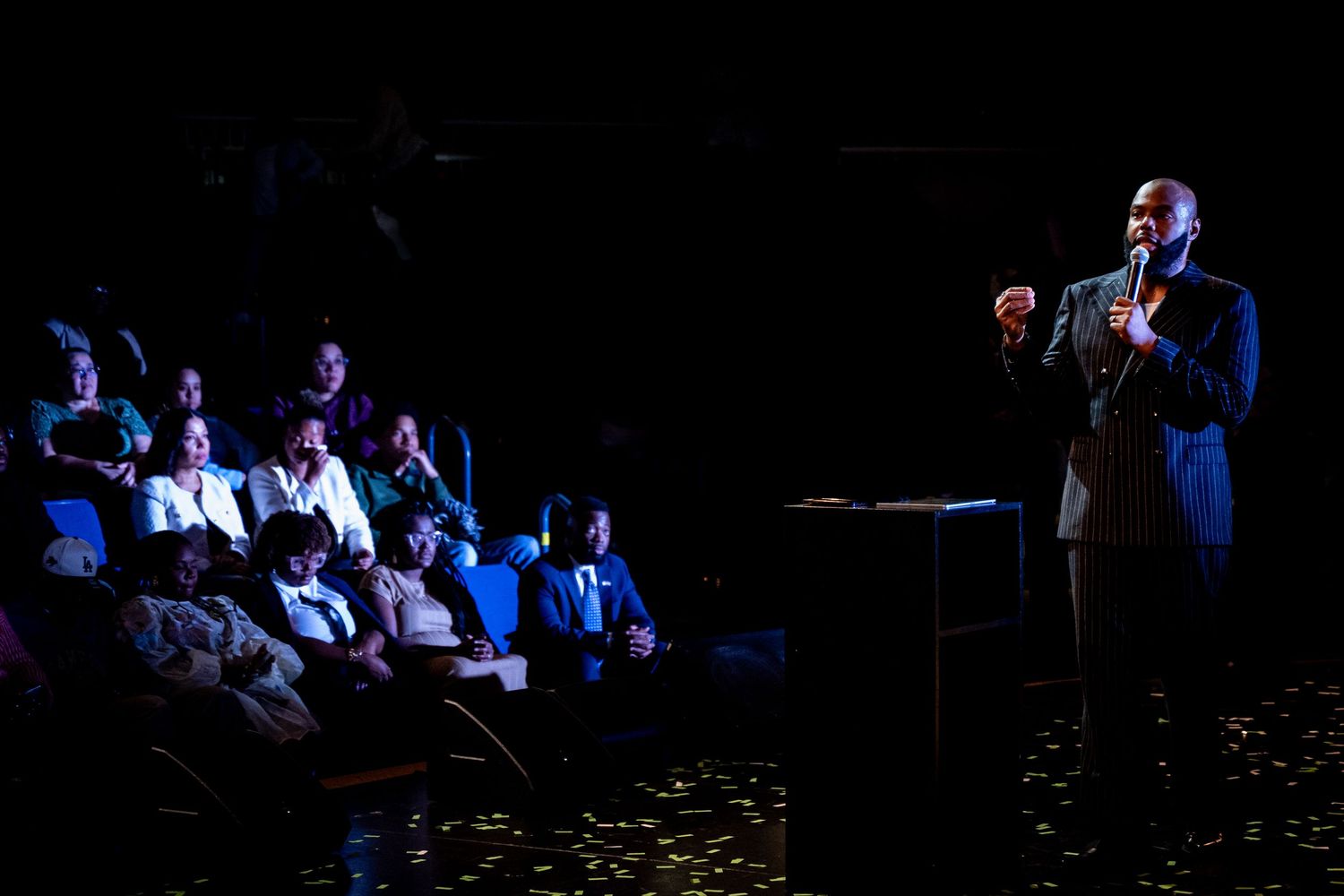 Performers on a dark stage illuminated by blue lighting during a theatrical production.