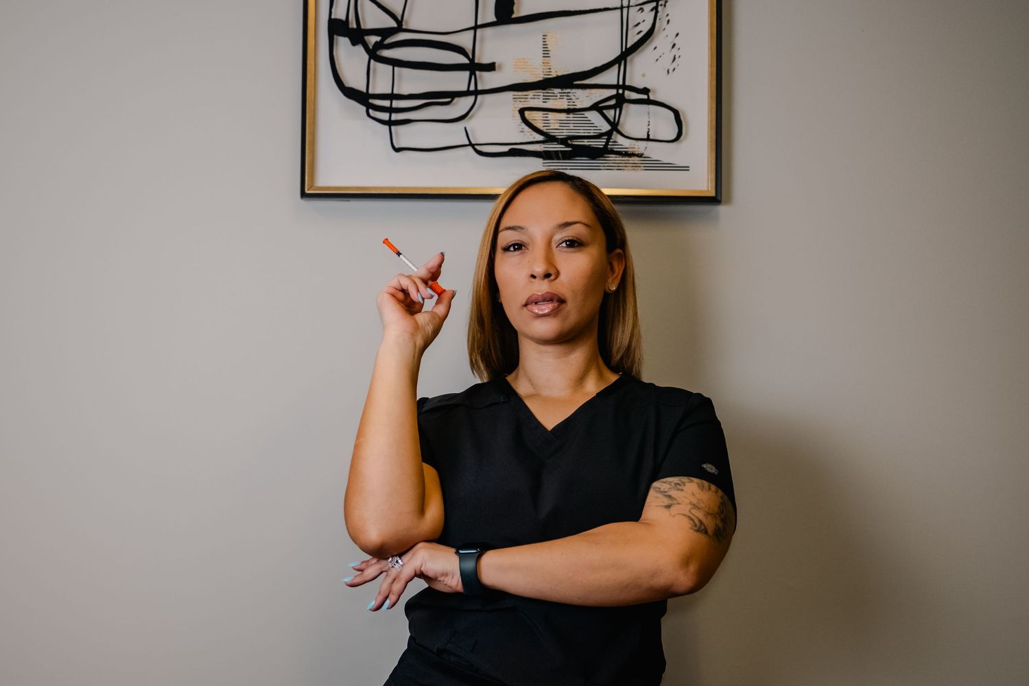 Professional in black attire gesturing with confidence against a wall with modern artwork.