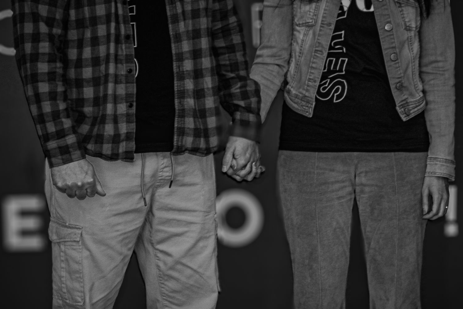 Black and white image of two people holding hands in casual clothing.