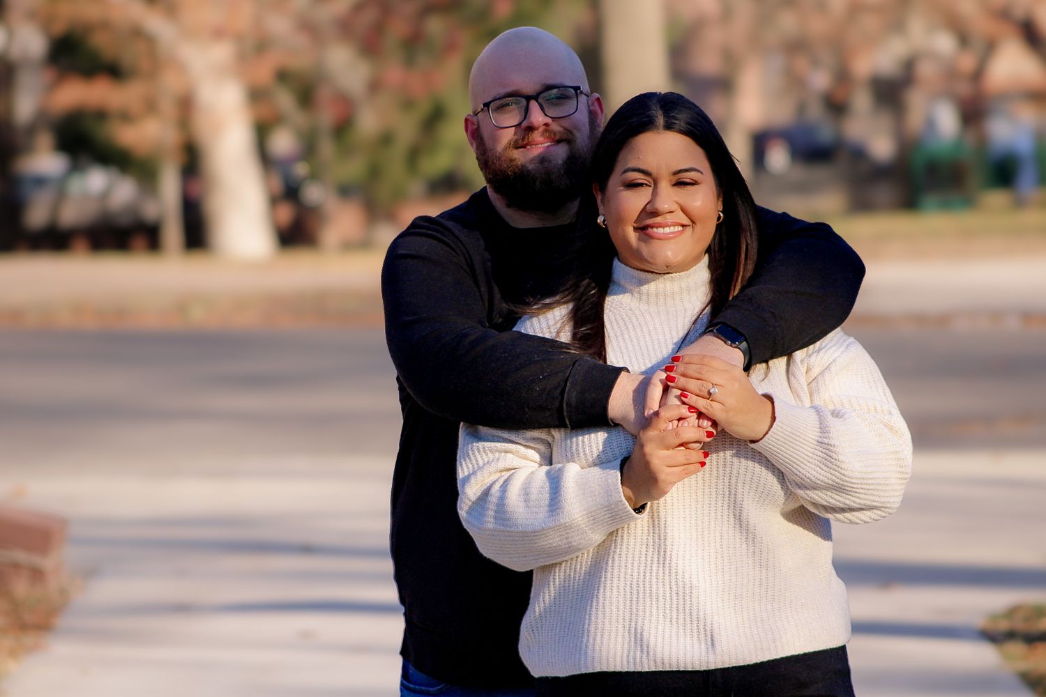 A cozy winter embrace captured outdoors with bare trees in the background.