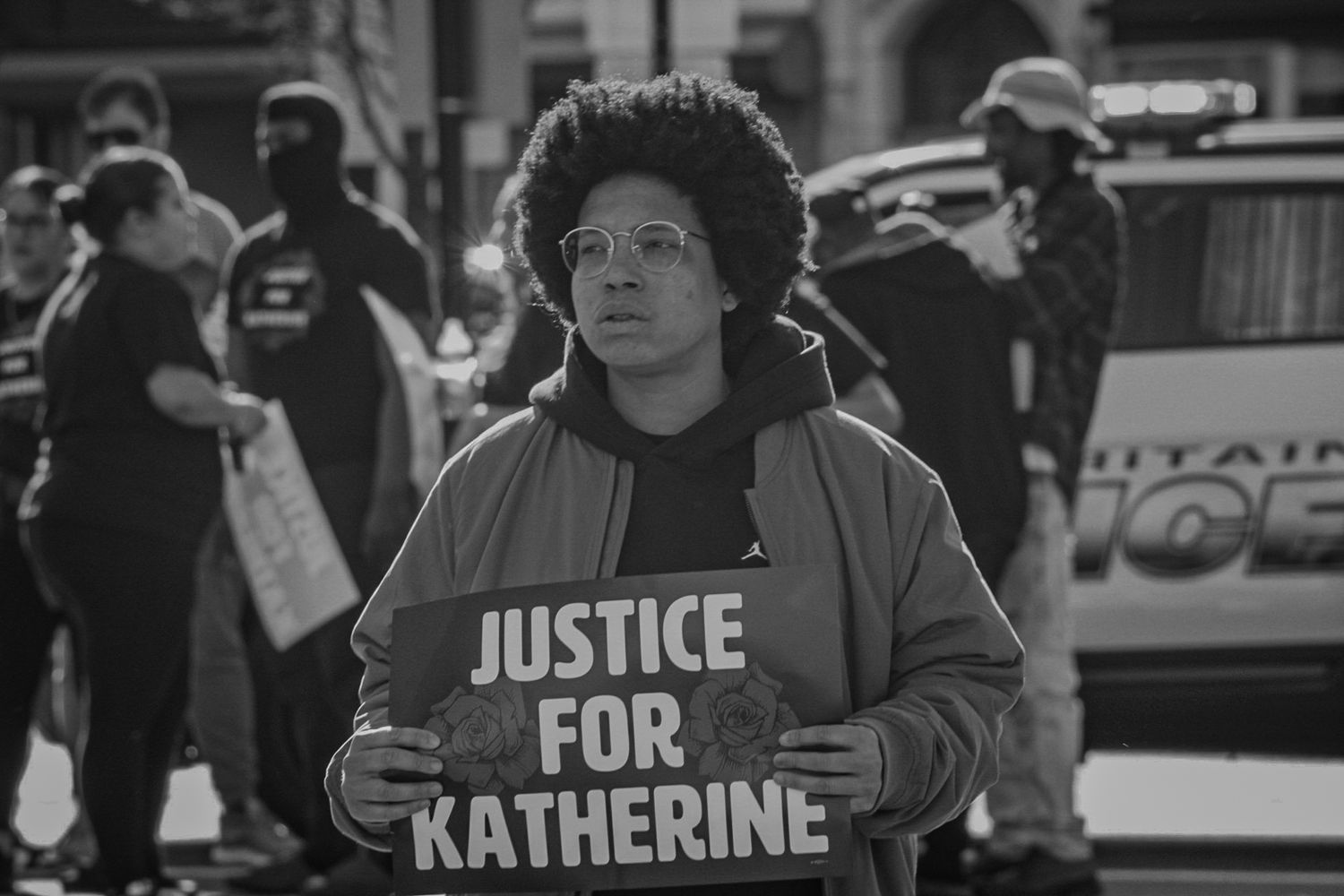 Black and white image of protesters holding signs demanding justice at street demonstration.