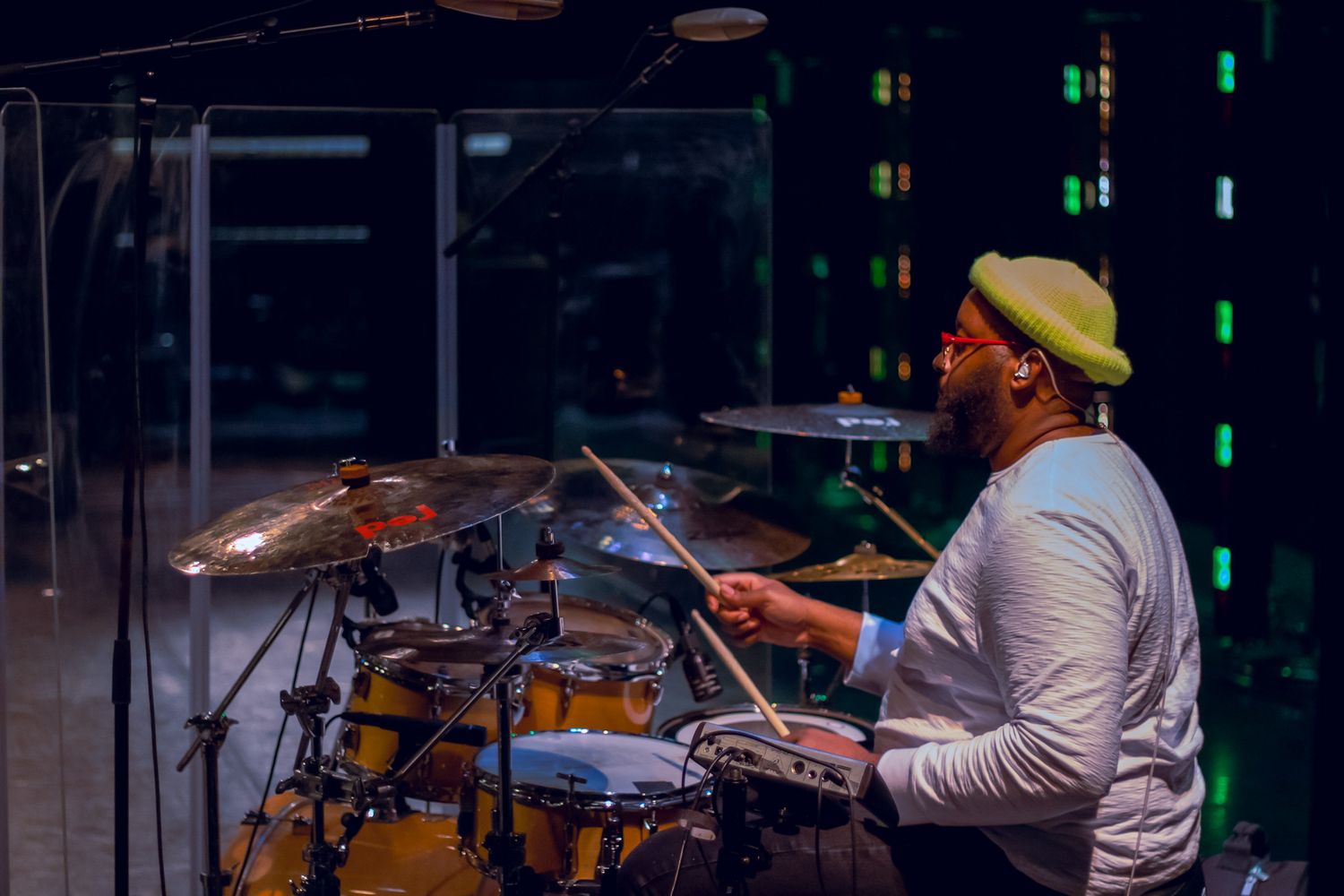 Drummer performs on stage with colorful lighting and professional drum kit setup.