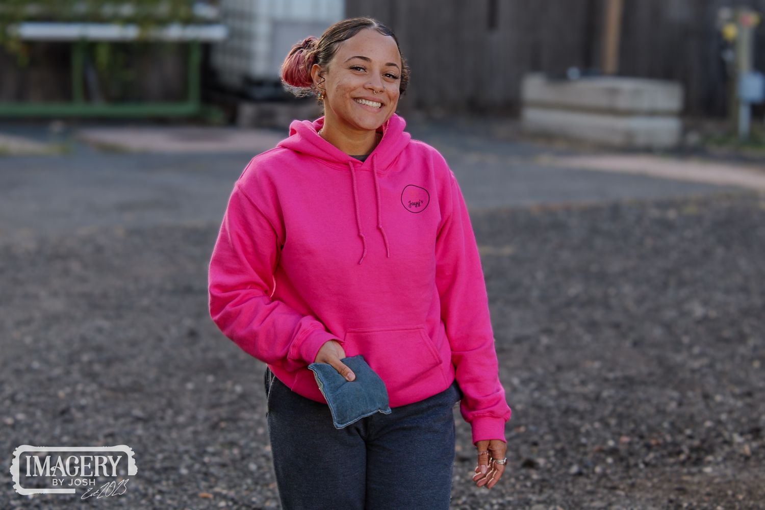 Person wearing bright pink hoodie smiling while standing outdoors.