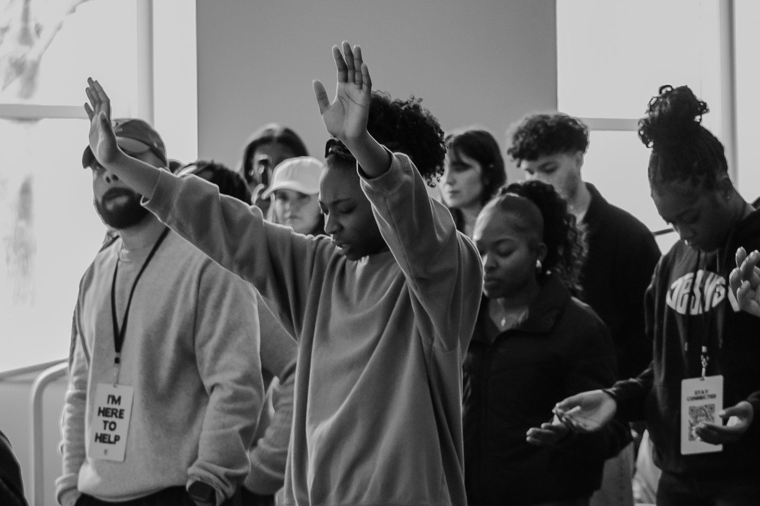 Group of people raising hands in worship during black and white photography.