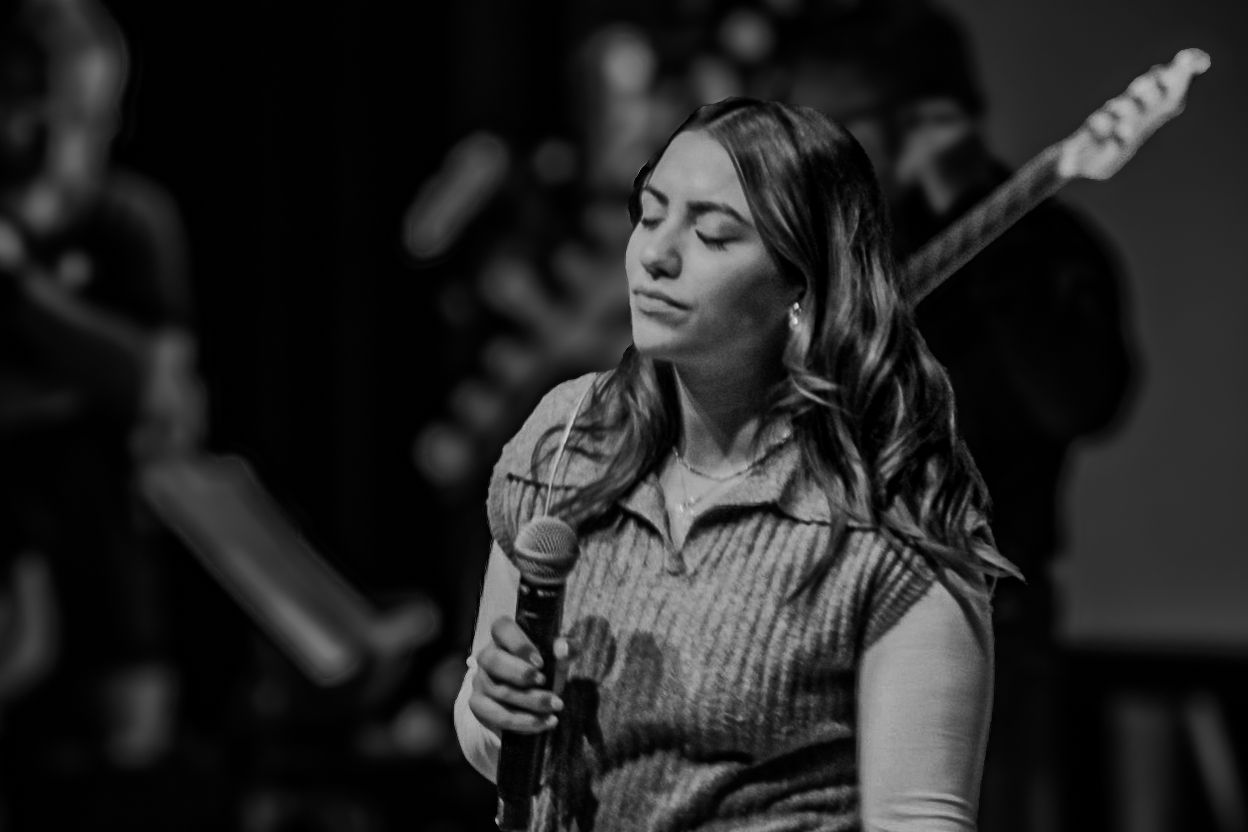 Black and white portrait of singer performing with microphone on stage.