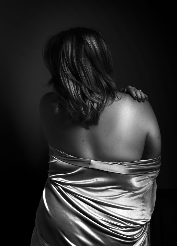zwart-witportret van blote schouders gedrapeerd in zijdeachtige stof boudoirfotografie zeewolde